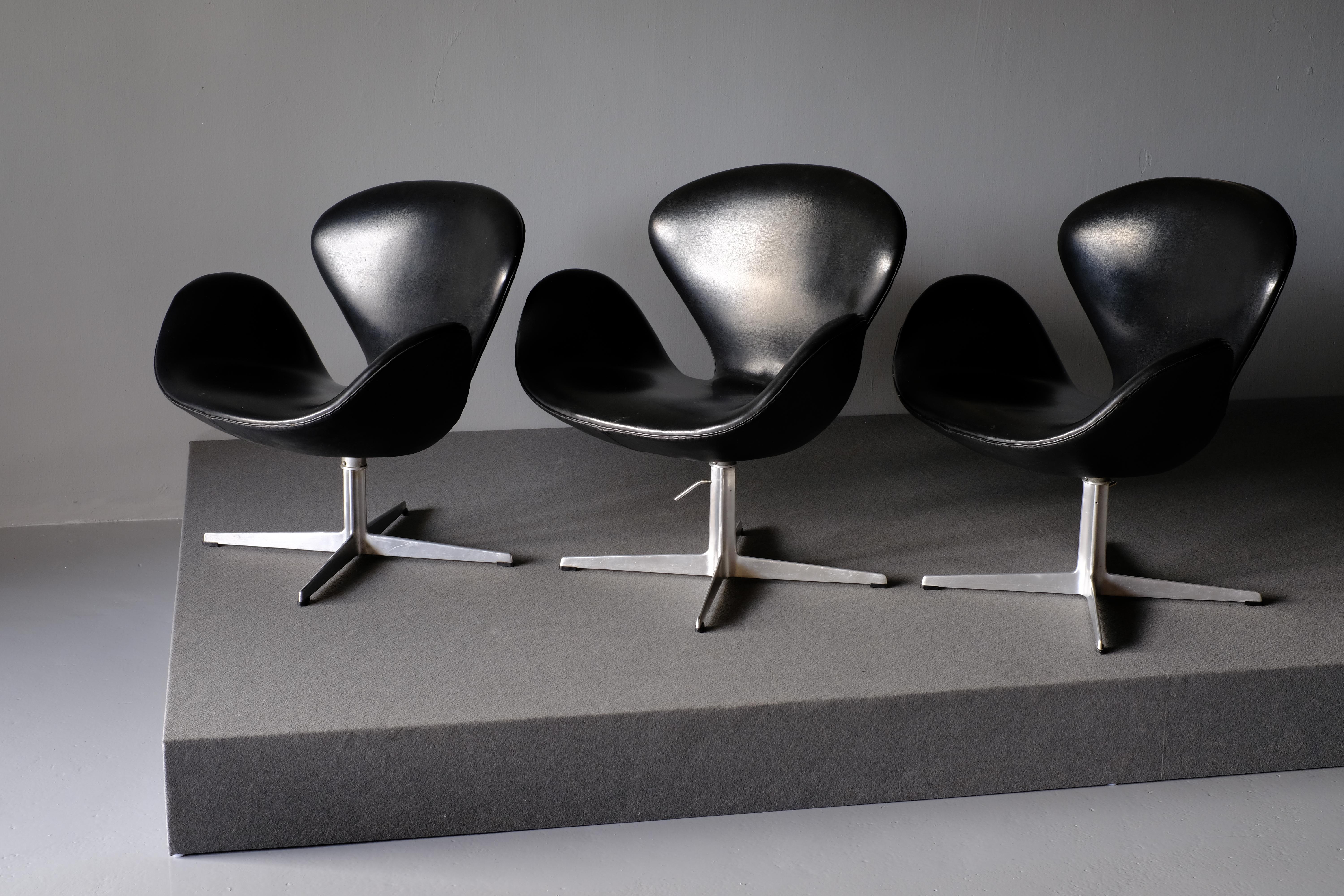 This early example of The Swan lounge chair model 3320 was designed by Arne Jacobsen for the SAS Royal Copenhagen Hotel which opened in 1960. It is produced by Fritz Hansen. It is upholstered in black Skai which is beautifully patinated. It has a