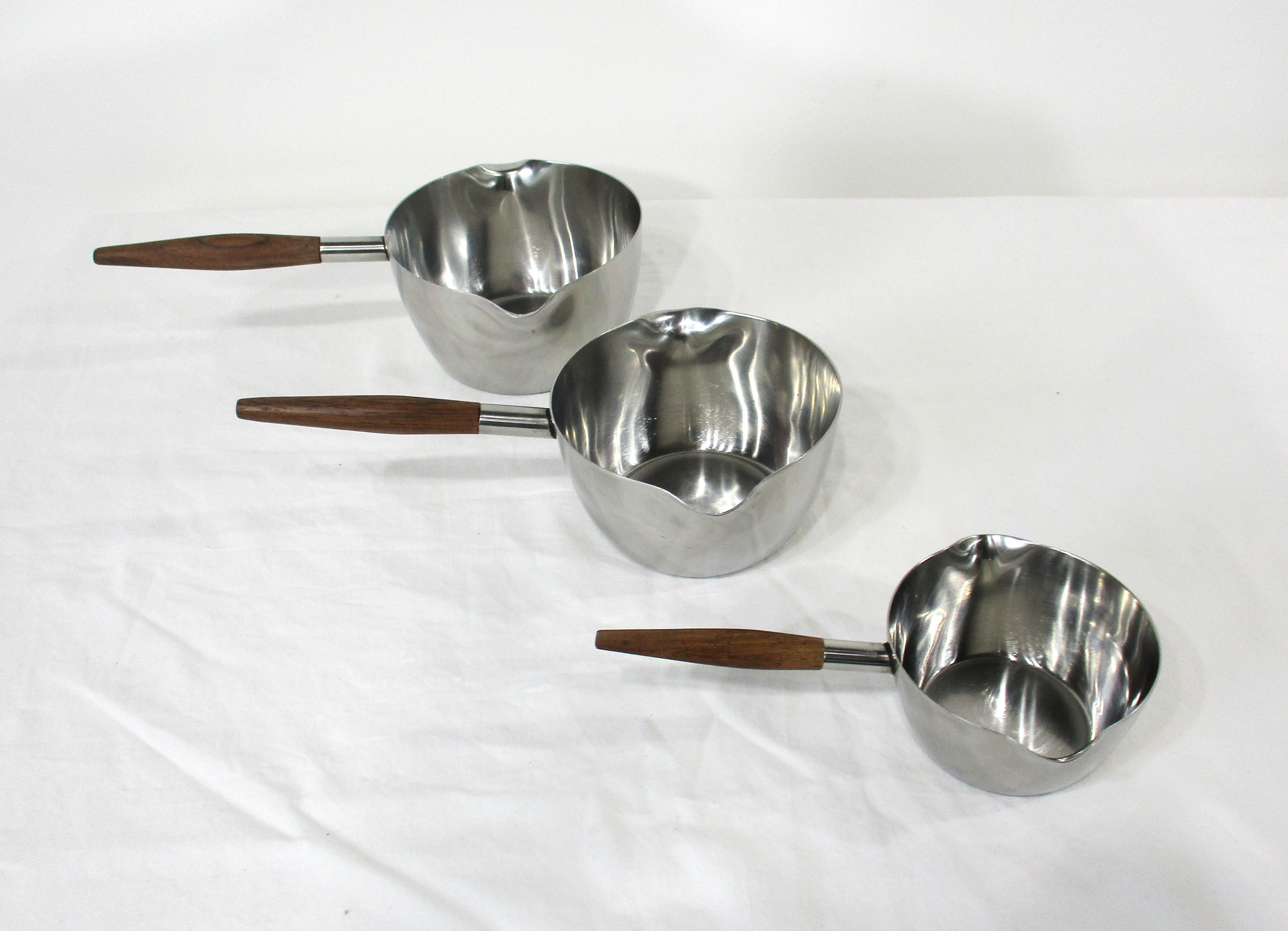 Un ensemble de trois saucières sculpturales en acier inoxydable du milieu du siècle avec des poignées en teck. Conçue à la manière d'Arne Jacobsen et fabriquée au Danemark par Dana, elle sera du plus bel effet sur votre table pour servir vos sauces