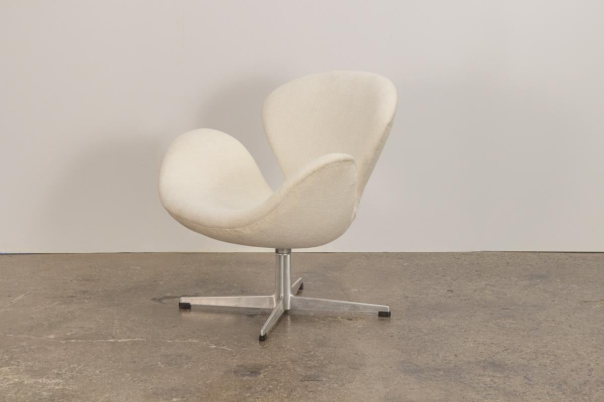 The iconic Swan chair designed by Arne Jacobsen for Fritz Hansen. Attractive, ergonomic curves designed to sheathe it's sitter and follow resting limbs. Sits on brushed aluminum swiveling four-star base for additional height. Nicely upholstered in a