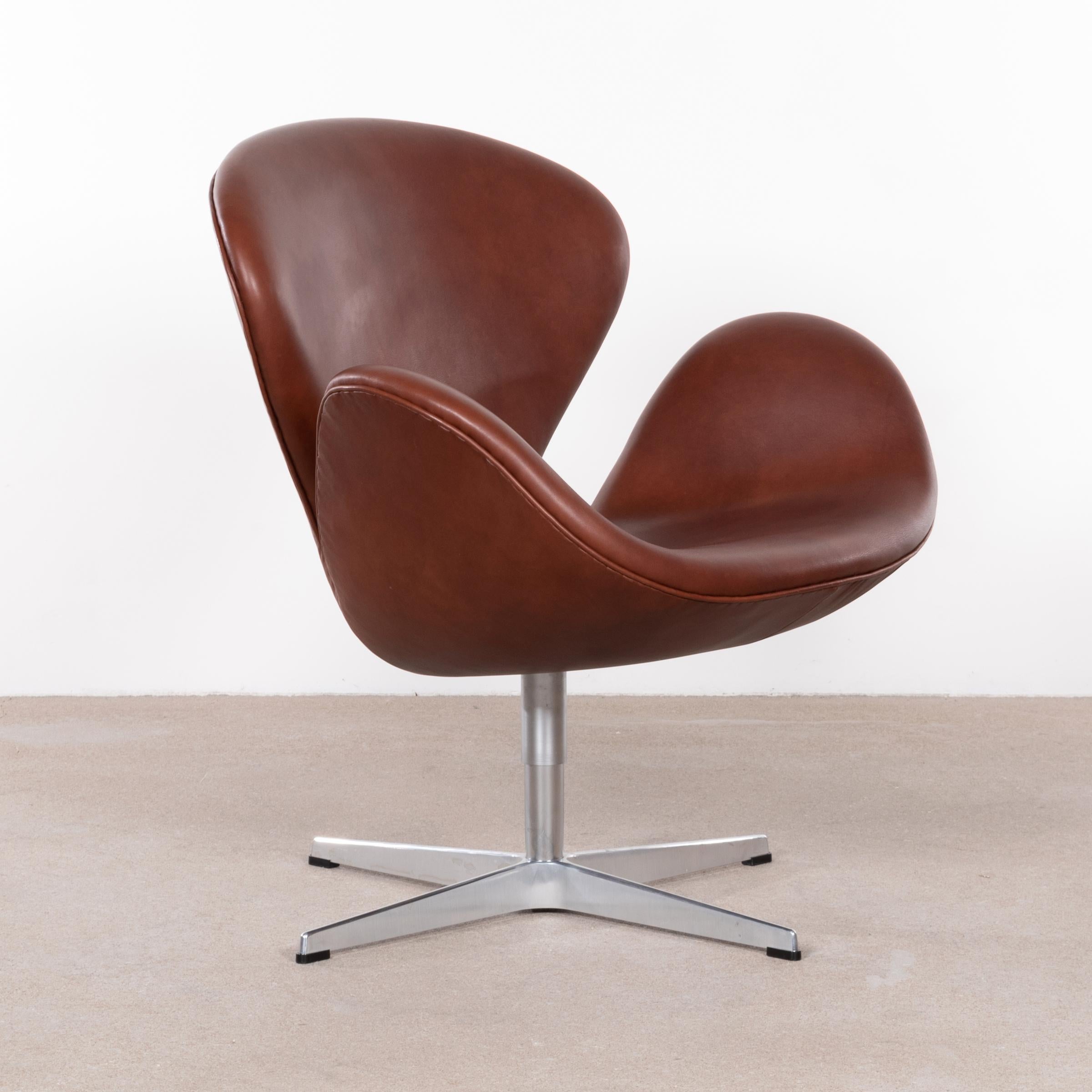 Iconic swan chair by Arne Jacobsen for Fritz Hansen (Denmark 2006). Original designed for the Hotel Royal in Copenhagen late 1950s. The chair is upholstered in a soft chestnut brown premium leather and is in very good / excellent condition with only