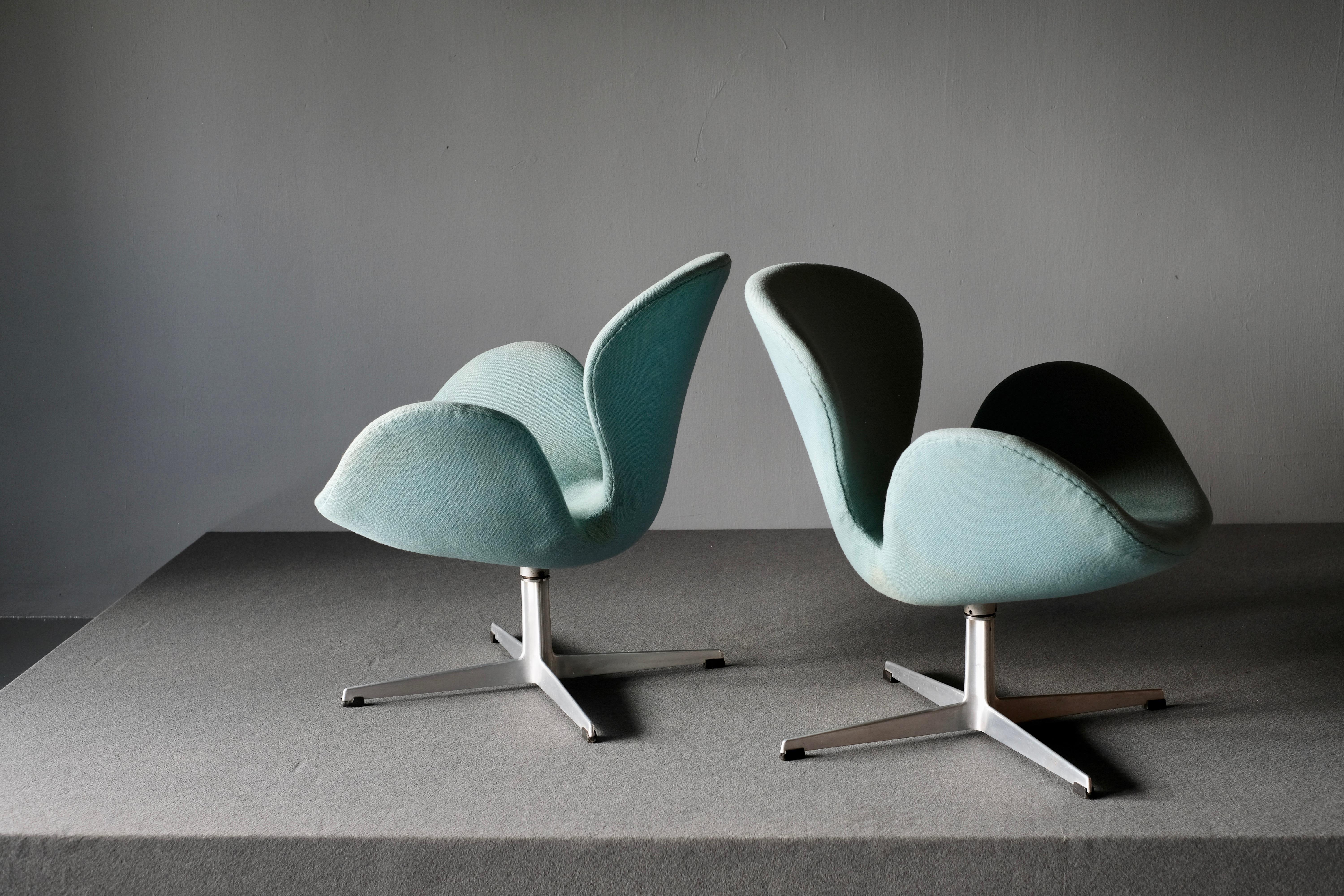 A matching pair of Swan lounge chairs model 3320. Designed by Arne Jacobsen for the SAS Royal Copenhagen Hotel which opened in 1960. It is produced by Fritz Hansen. Each chair is upholstered in fully original distinctive pigeon blue upholstery. The