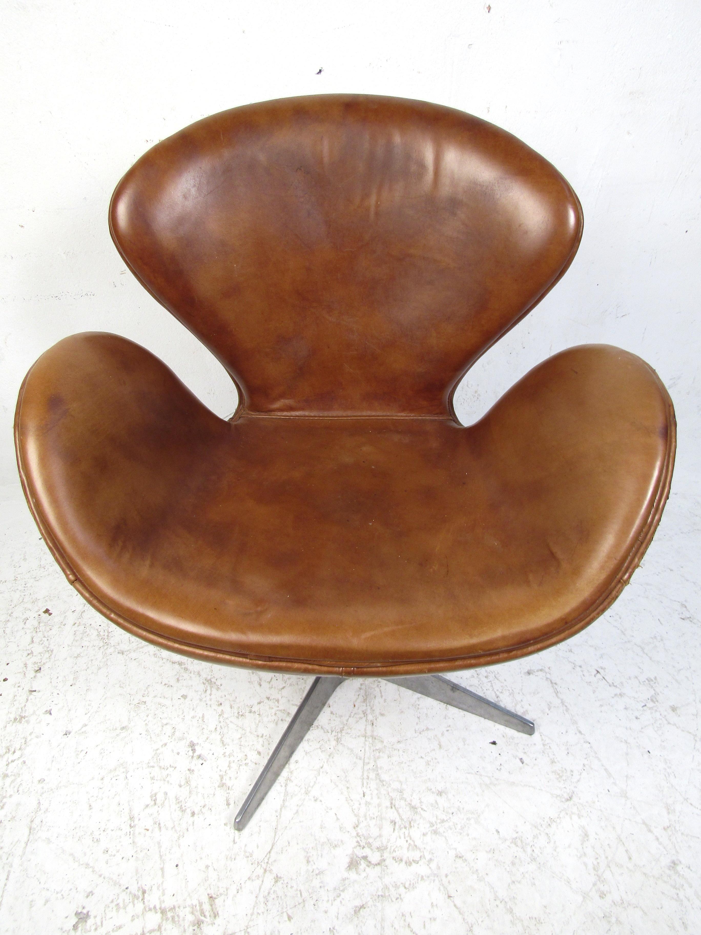 This beautiful Arne Jacobson brown leather swan chair is a must-have for any game or showroom. With plush gently worn leather it is incredibly comfortable. The mid-century design will work with many different concepts, while perfectly accenting your