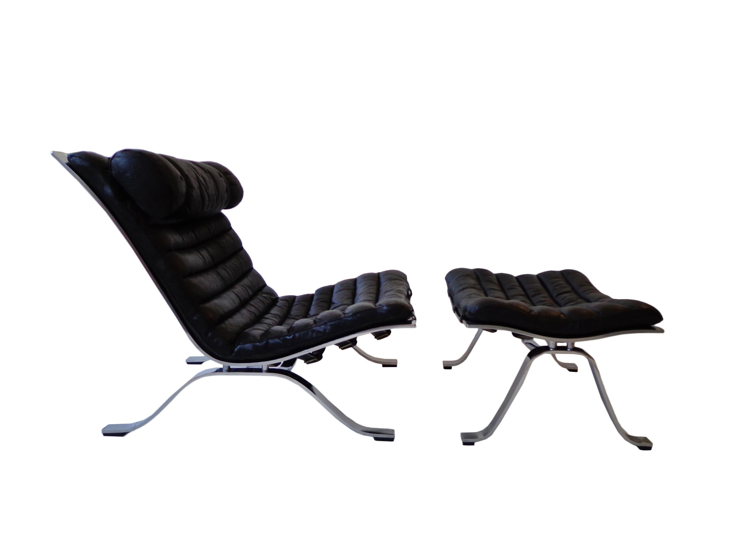 Comfortable lounge chair and ottoman designed by Arne Norell. This award winning lounge chair is made of high quality matt polished steel and original black leather. The set is in nice vintage condition with fantastic patina from age and