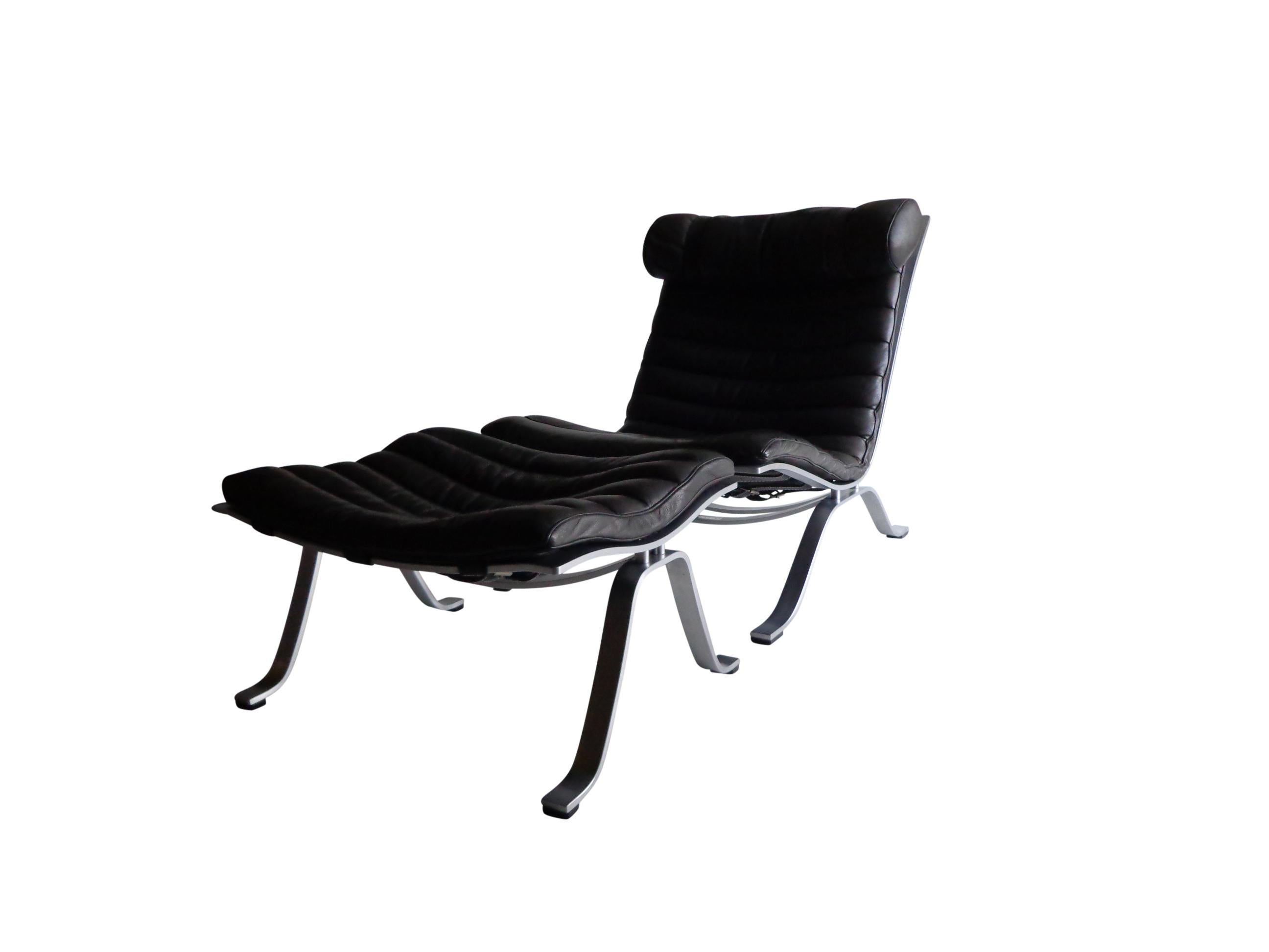 Comfortable lounge chair and ottoman designed by Arne Norell. This award winning lounge chair is made of high quality matt polished steel and original black leather. The set is in nice vintage condition with fantastic patina from age and