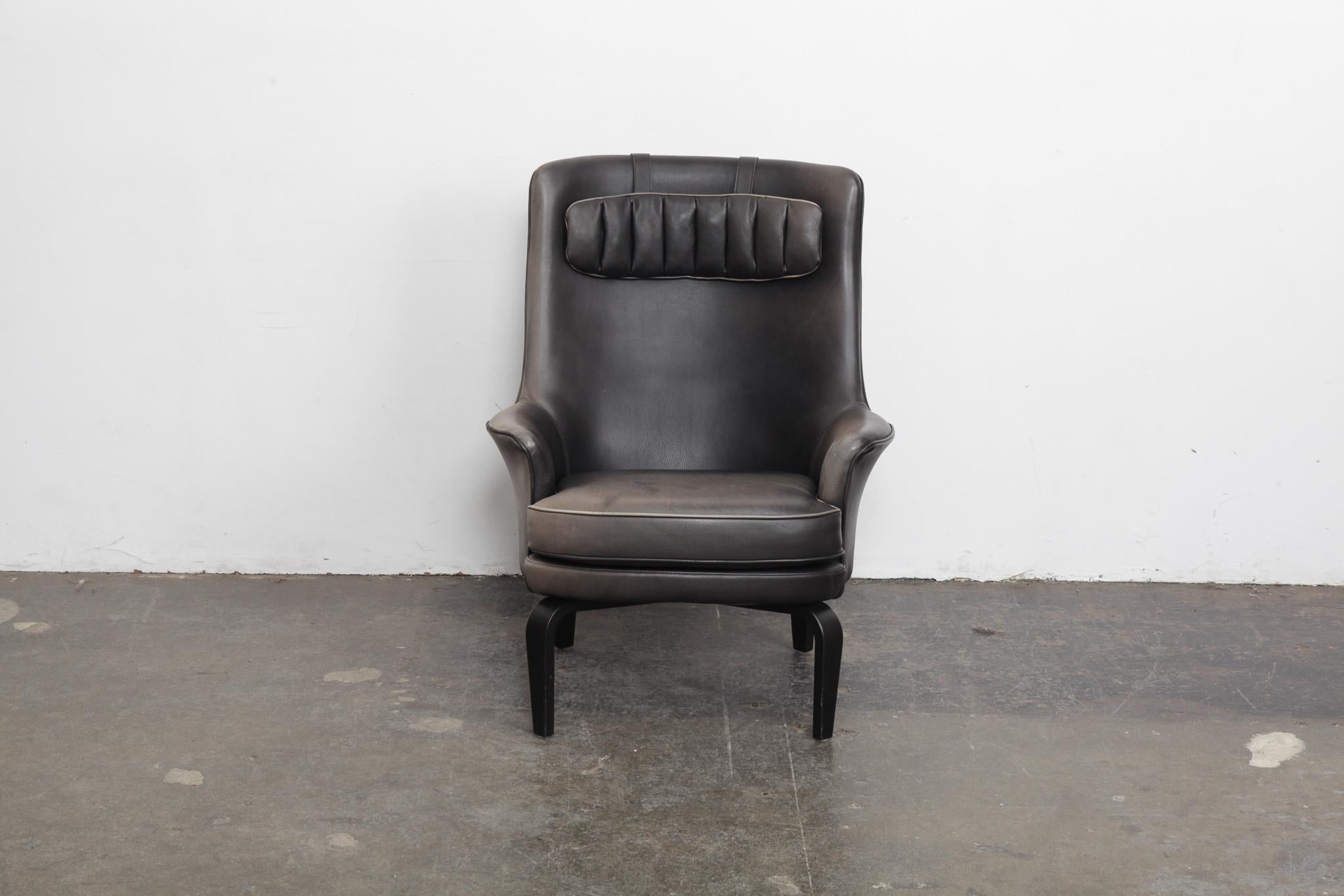 Swedish lounge chair in original black leather that has faded to a dark grey in many areas, designed by Arne Norell for Norell AB, model 'Pilot'. Ebonized beech bent wood legs and original headrest as well.