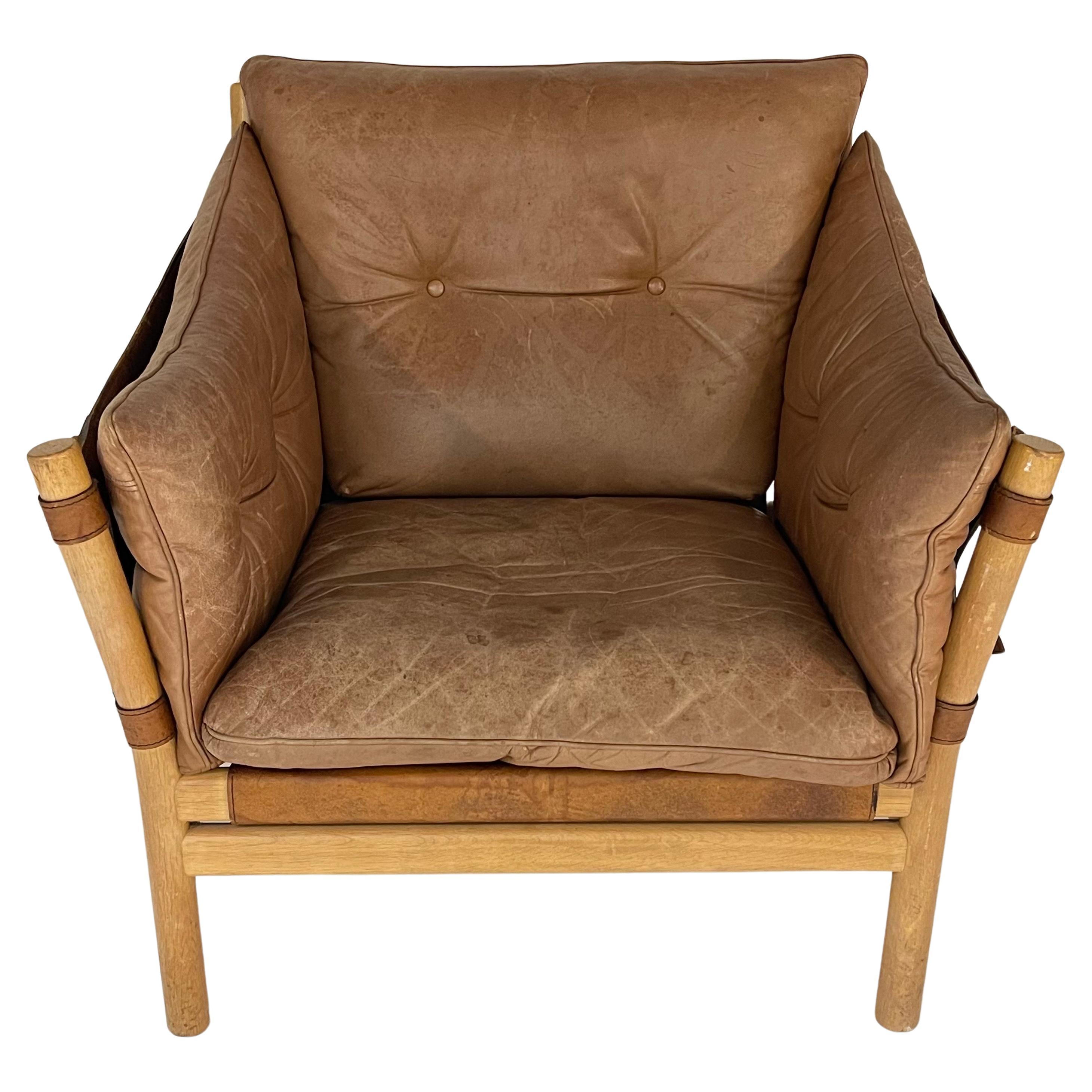 Rare Ilona campaign safari chair rendered in a turned oak frame with cognac leather back, side, buckle straps and button removable loose cushions.  Designed by Arne Norell, Sweden, 1970s.