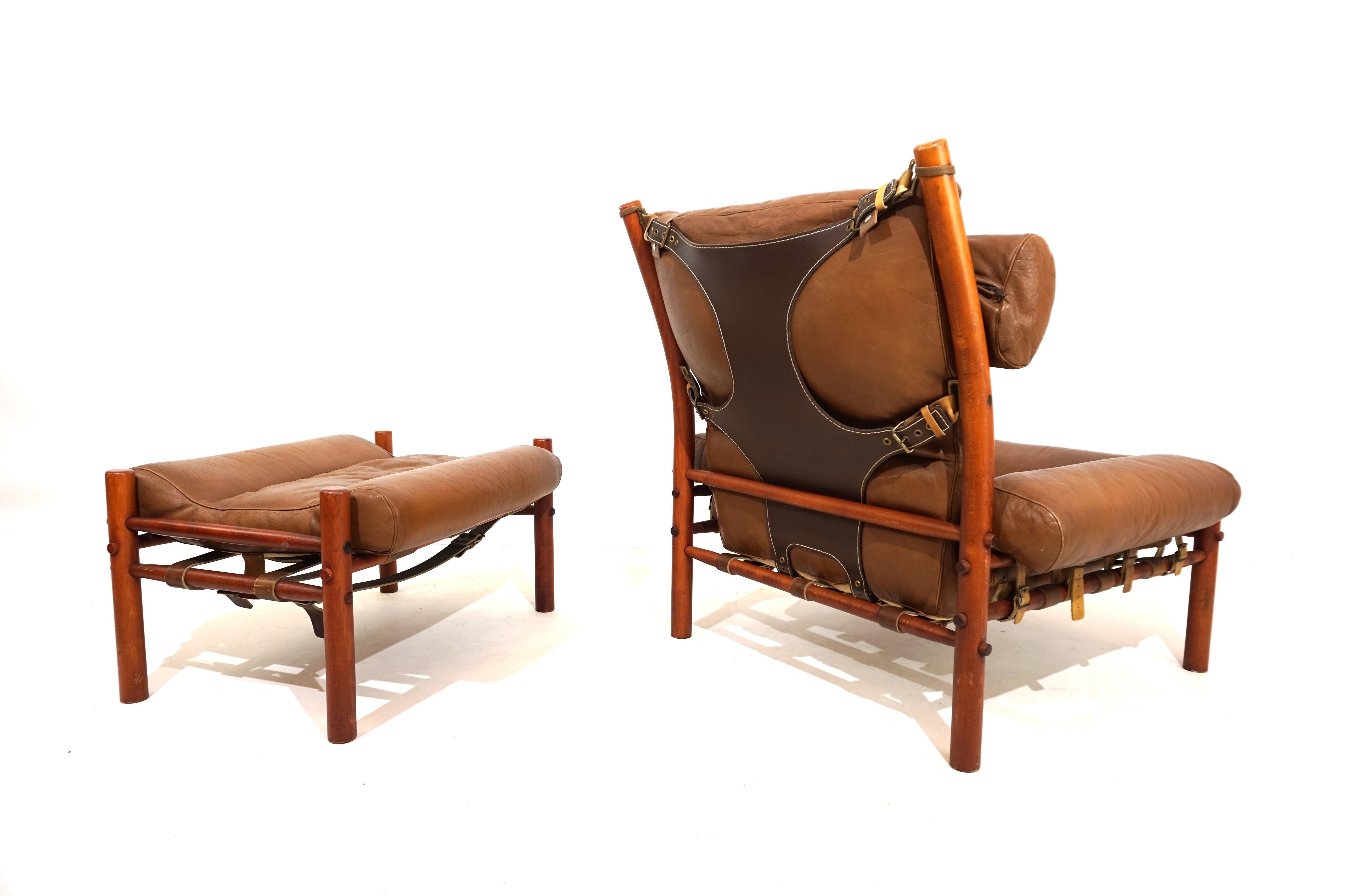 This Inka armchair with ottoman made of caramel-colored aniline leather with dark brown, strong leather on the back comes in excellent condition. The original leather of the armchair and the ottoman is flawless, all fasteners and leather straps are