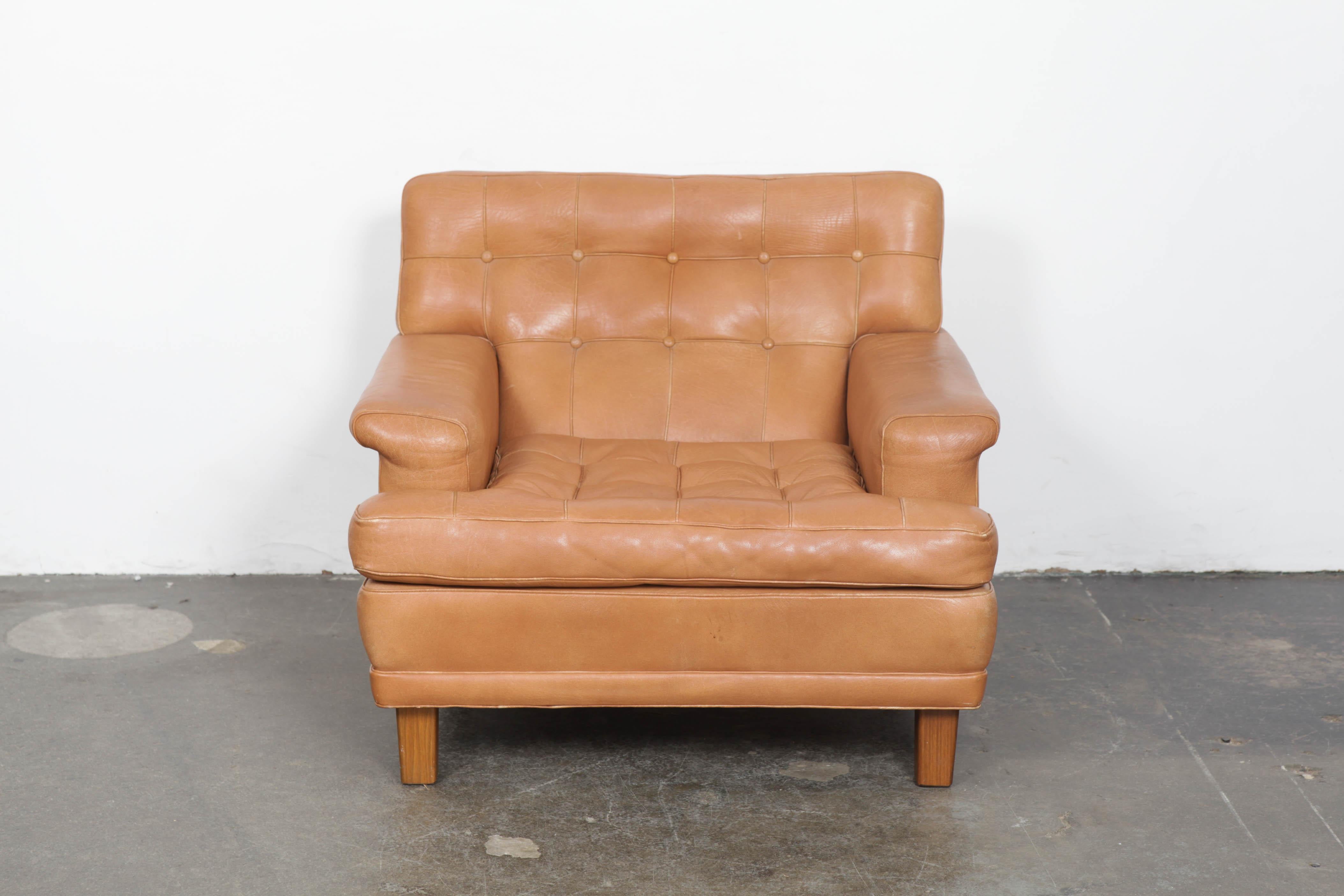 Beautiful tan color tufted and panelled leather lounge chair by Arne Norell for Norell AB, Sweden, in original leather, model 'Merkur'. Minor wear consistent with age, the leather has no tears, rips or other actual damage.