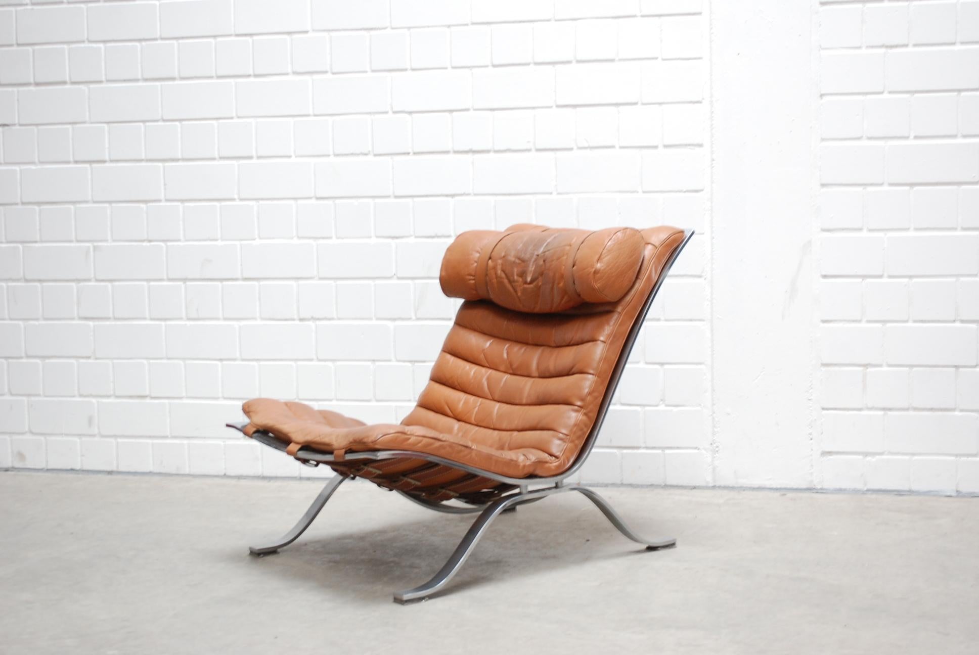 This Ari lounge chair was designed and produced by Arne Norell in Sweden.
It is made in chromed steel and cognac brandy leather upholstery.
Great leather details with belt and thick saddle leather.
A very comfortable chair.
 