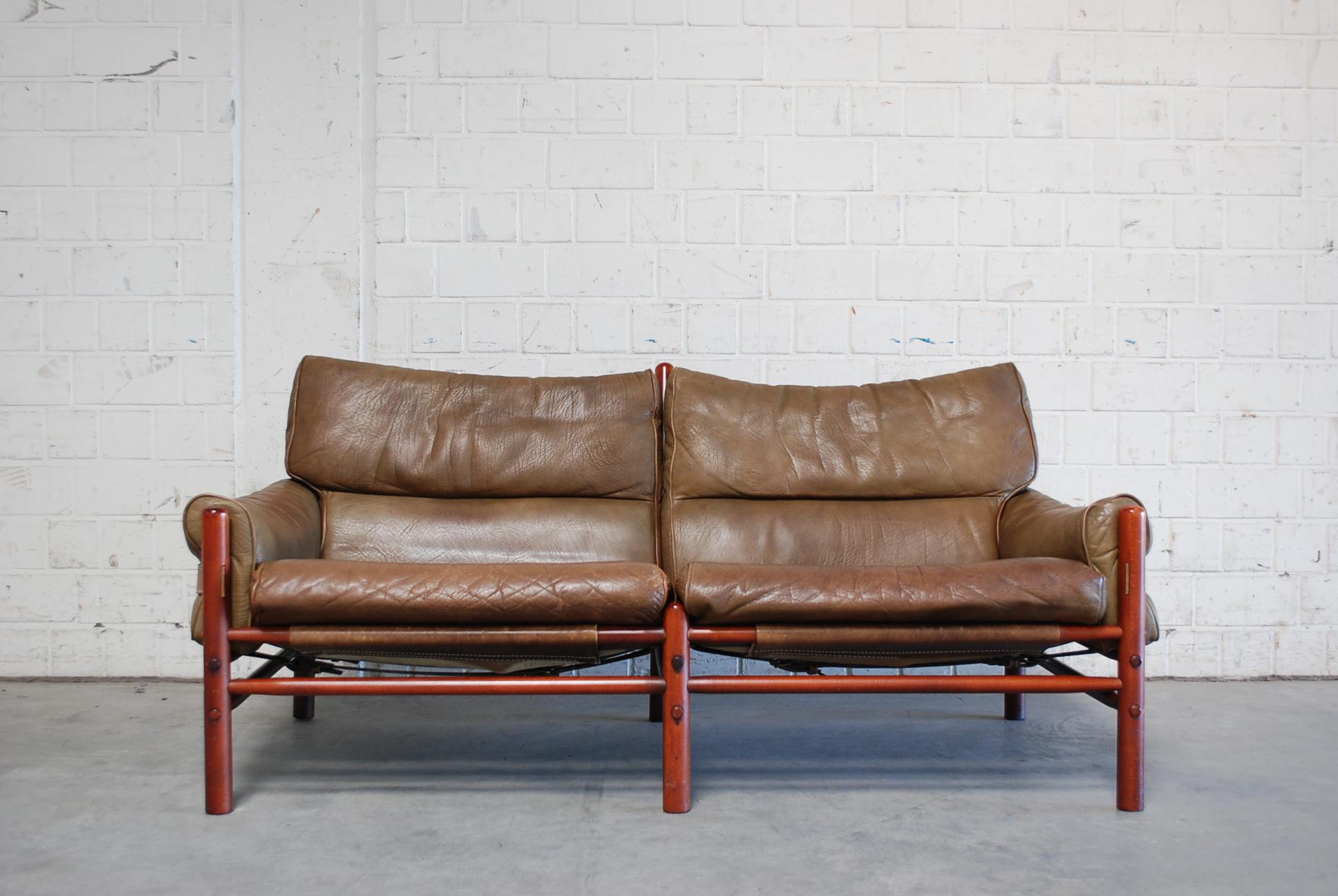 This brown olive leather Kontiki lounge sofa was designed and produced by Arne Norell in Sweden.
It is made from beech and stained in a teak color with original brown leather upholstery.
Great leather details in brass and belt and thick leather.
 