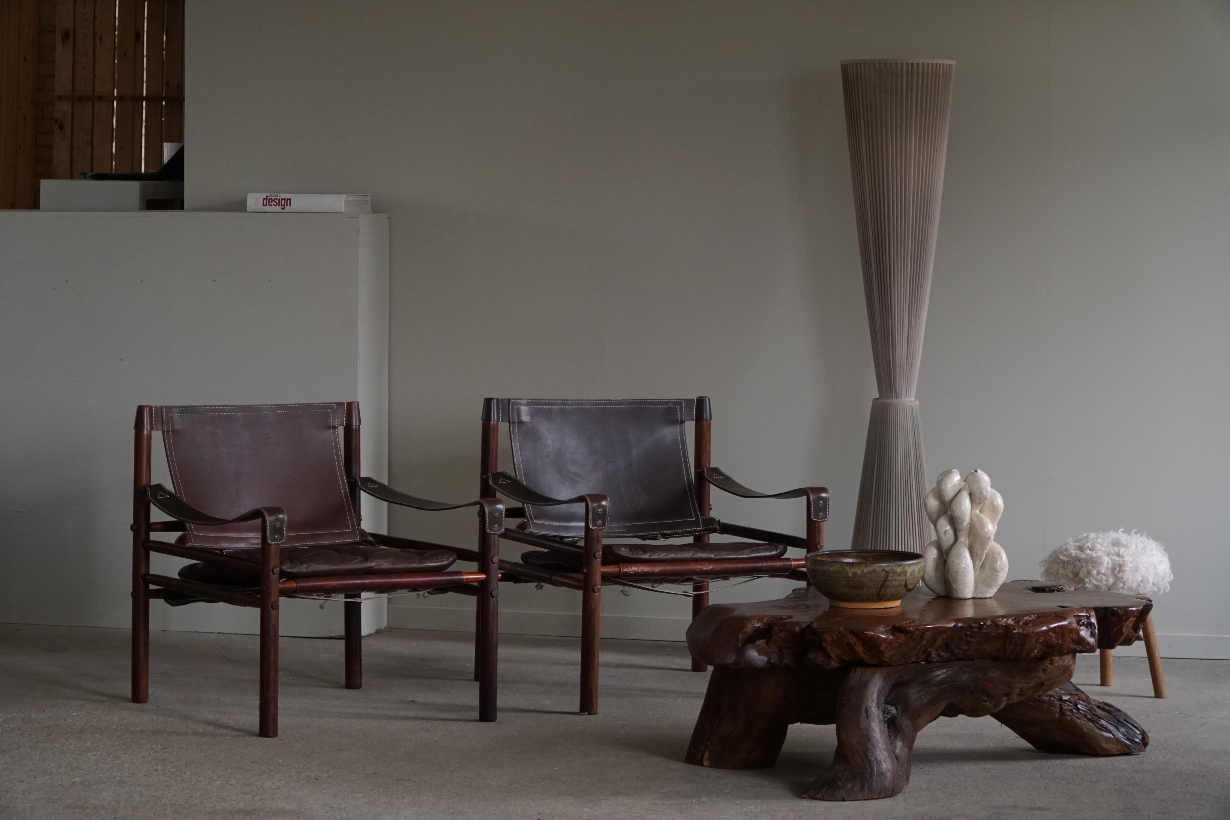 A stunning pair of safari chairs in dark brown leather and solid rosewood with beautiful wood grains. 
Designed by Arne Norell, produced by Arne Norell AB in Aneby, Sweden, in the 1960s.
These were manufactured in the 1960s.

These fine chairs
