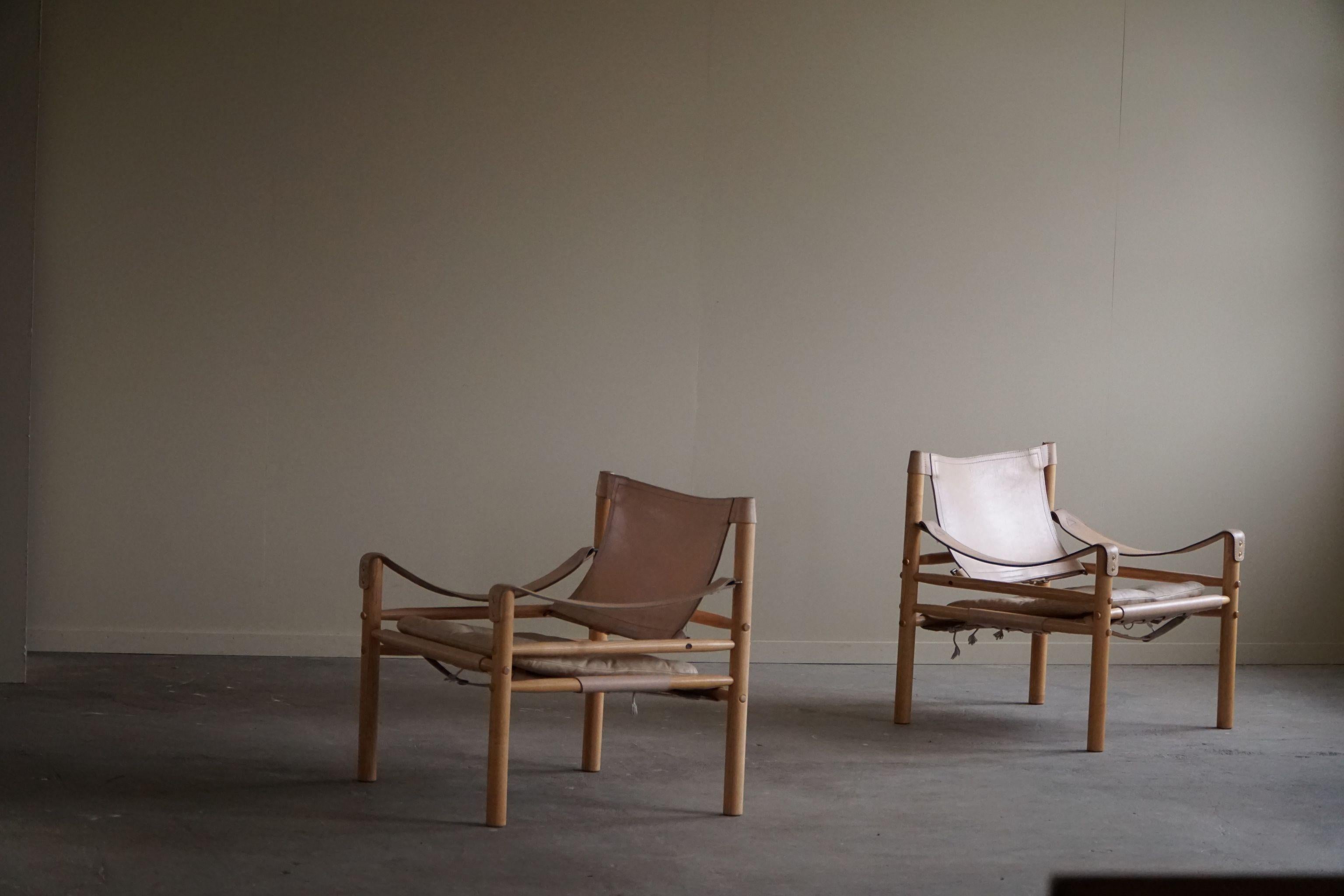Une belle paire de chaises safari en cuir crème et structure en frêne. Conçu par Arne Norell, produit par Arne Norell AB à Aneby, en Suède, dans les années 1960.

Ces fauteuils attrayants s'intègrent dans de nombreux styles d'intérieur. Une