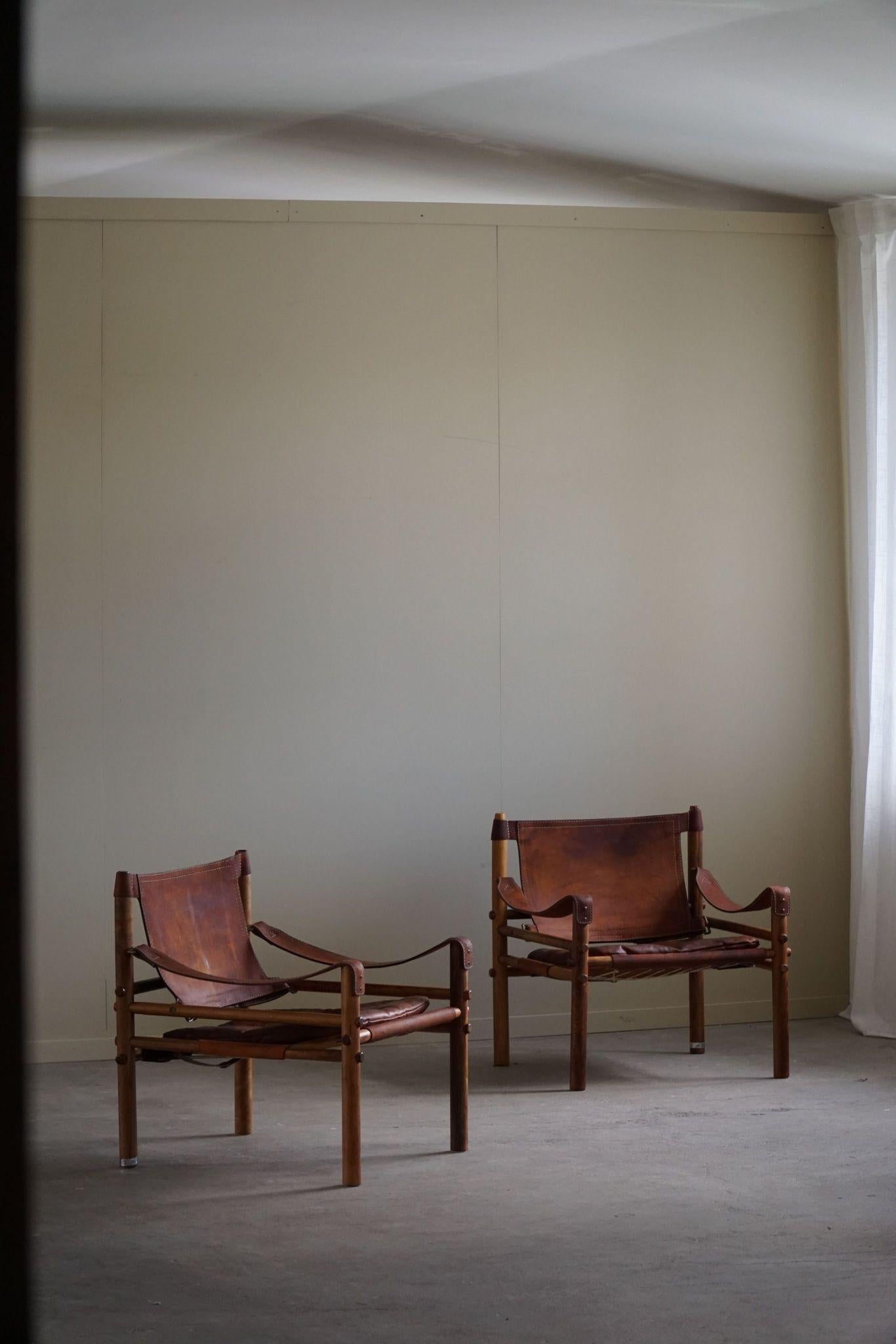 A beautiful pair of safari chairs in a warm red/brown leather and Brazilian rosewood frame with such wonderful wood grains.
Designed by Arne Norell, produced by Arne Norell AB in Aneby, Sweden, in the 1960s.

These appealing armchairs will fit into
