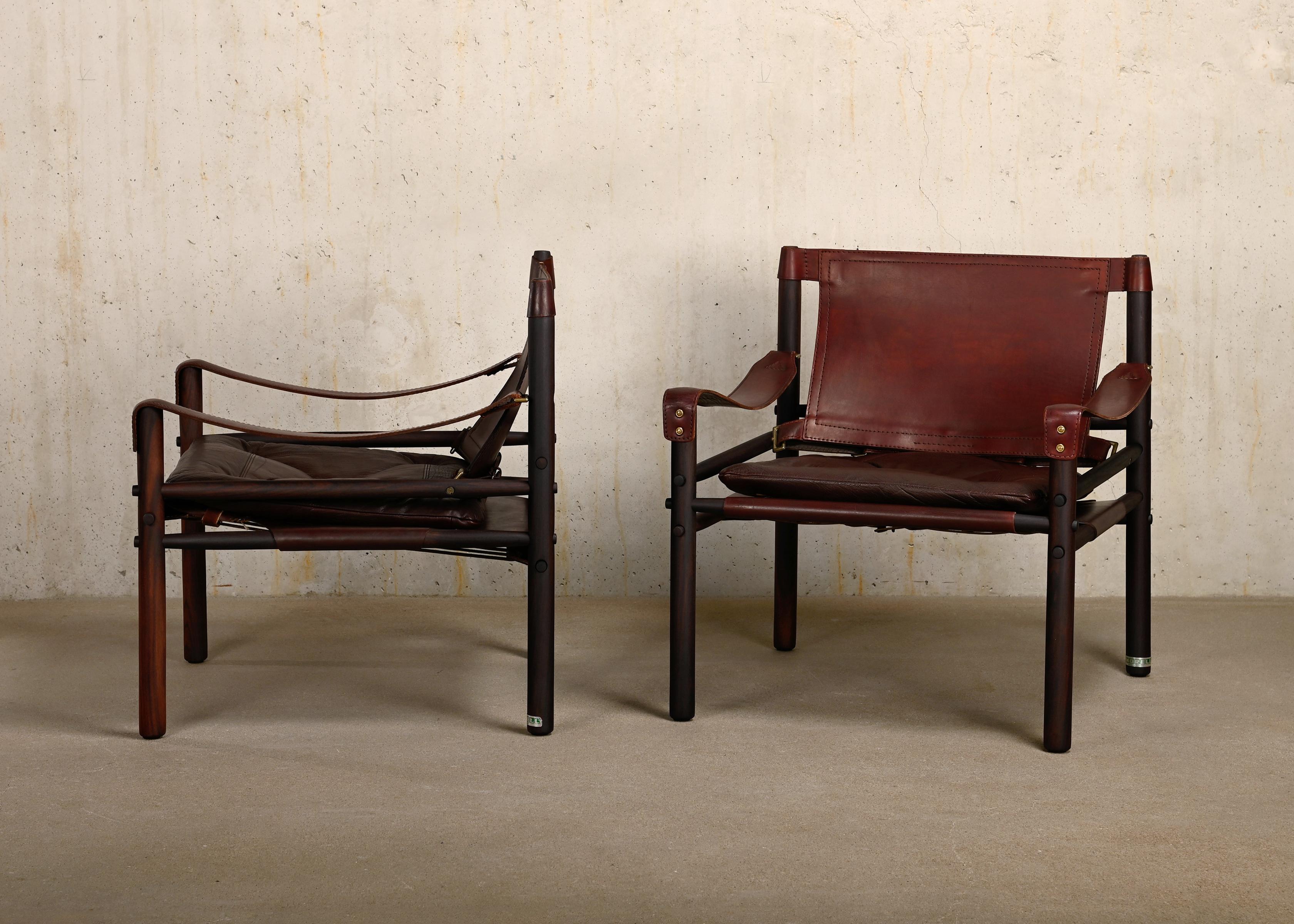 Great pair of Sirocco Safari Lounge Chairs designed by Arne Norell and manufactured by Norell Möbel AB in Sweden. Refinished rosewood frames with the original the leather cushions in beautiful patinated reddish chocolate brown leather. All in very