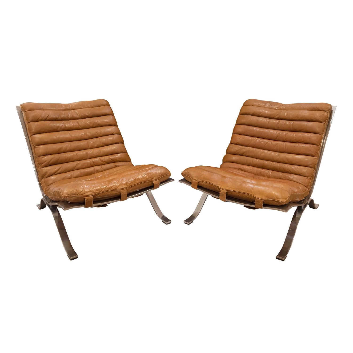 Rare pair of Ari Lounge Chairs in polished steel with original leather slings by Arne Norell for Arne Norell AB, Sweden 1960's (signed “Norell, Made in Sweden” on back metal). These chairs retain the original slings and belts on back. The color and
