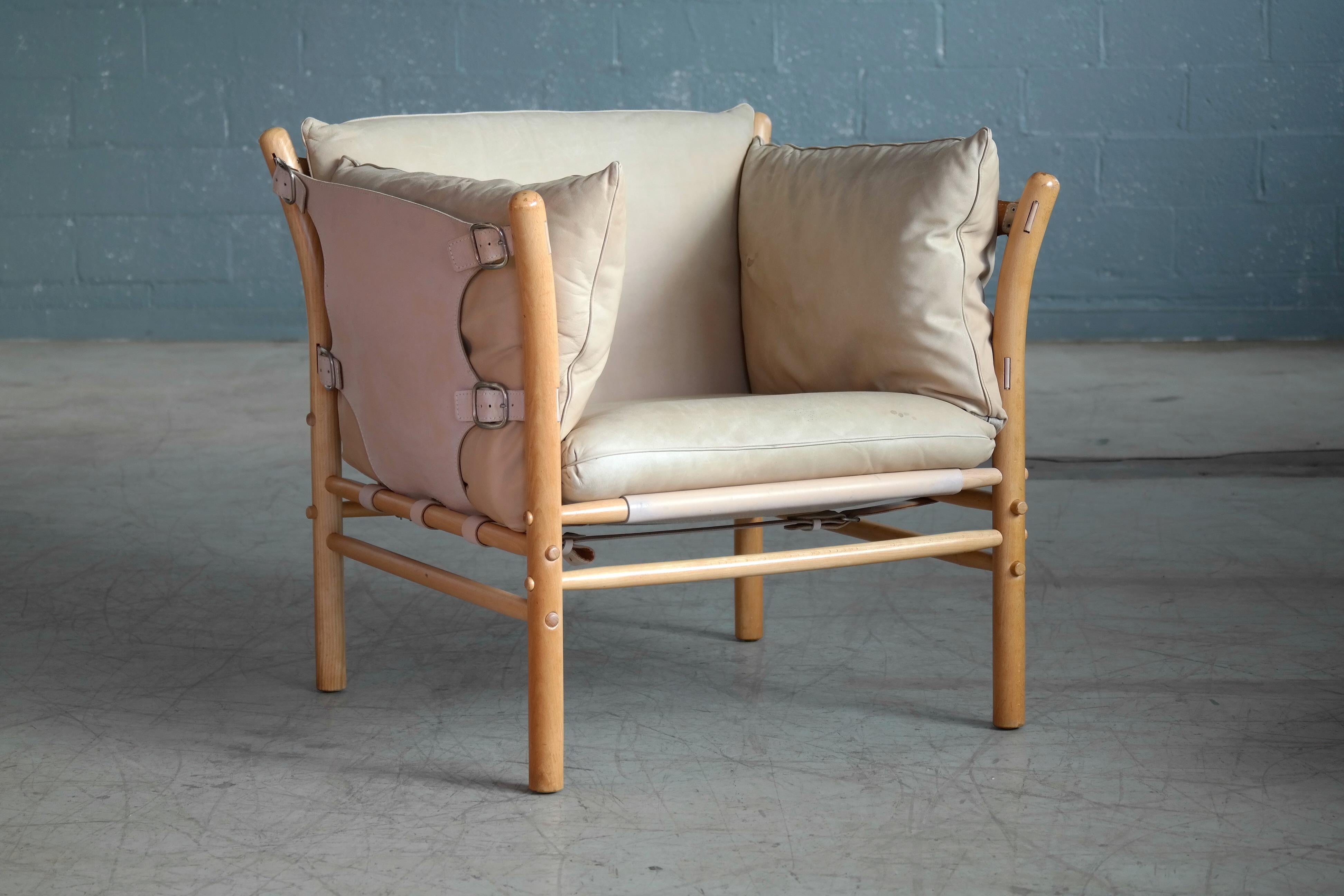 Beautiful 1960s safari chair in cream and tan leather and blond beech wood designed by Arne Norell in the 1960s for Norell Mobler, Sweden. The chair is assembled without any screws or hardware and held together by the heavy gauge saddle leather with