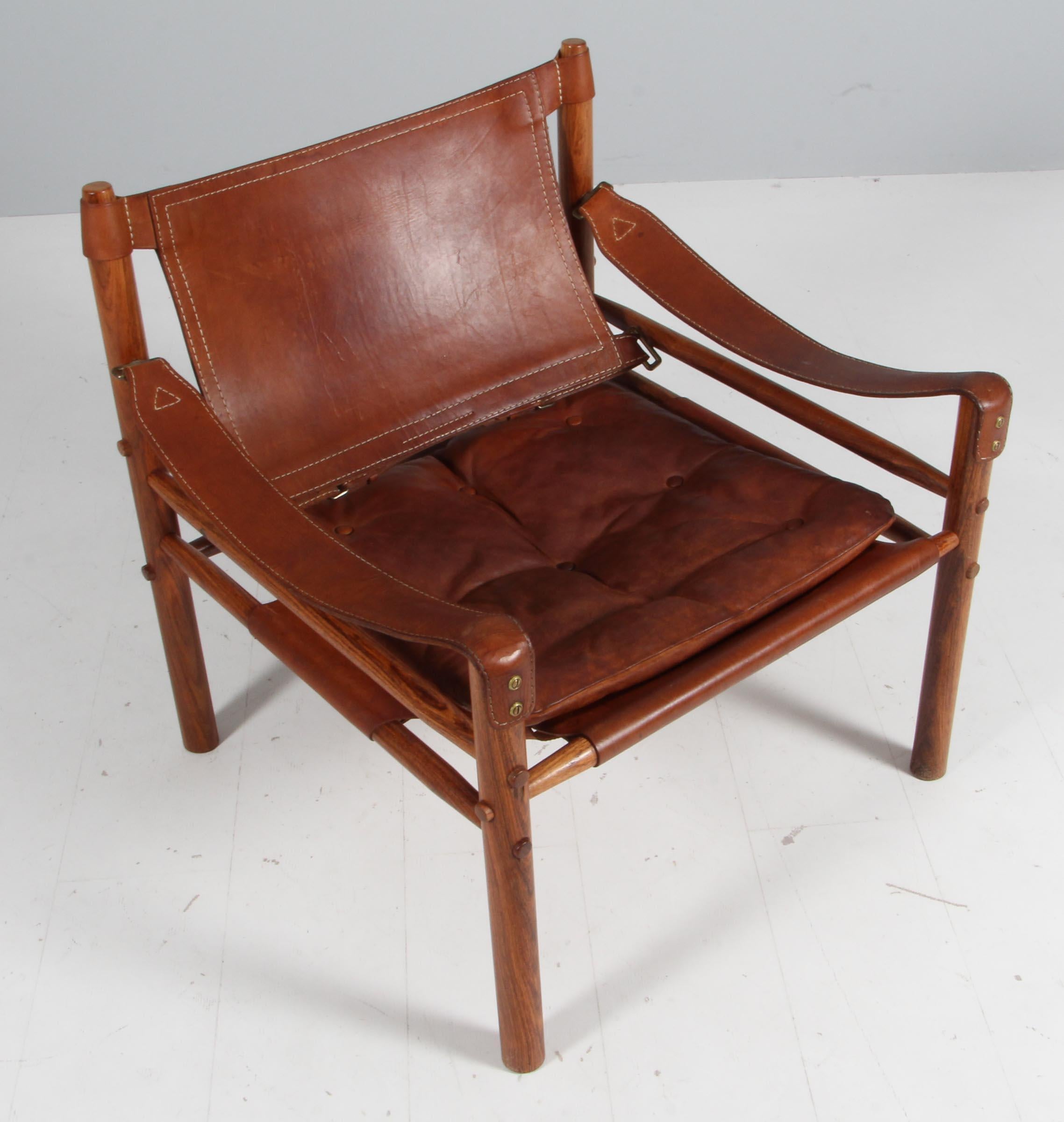 Arne Norell safari chair. Original upholstered foam cushions with patinated leather.

Frame of rosewood.

Model Scirocco, made by Norell.
