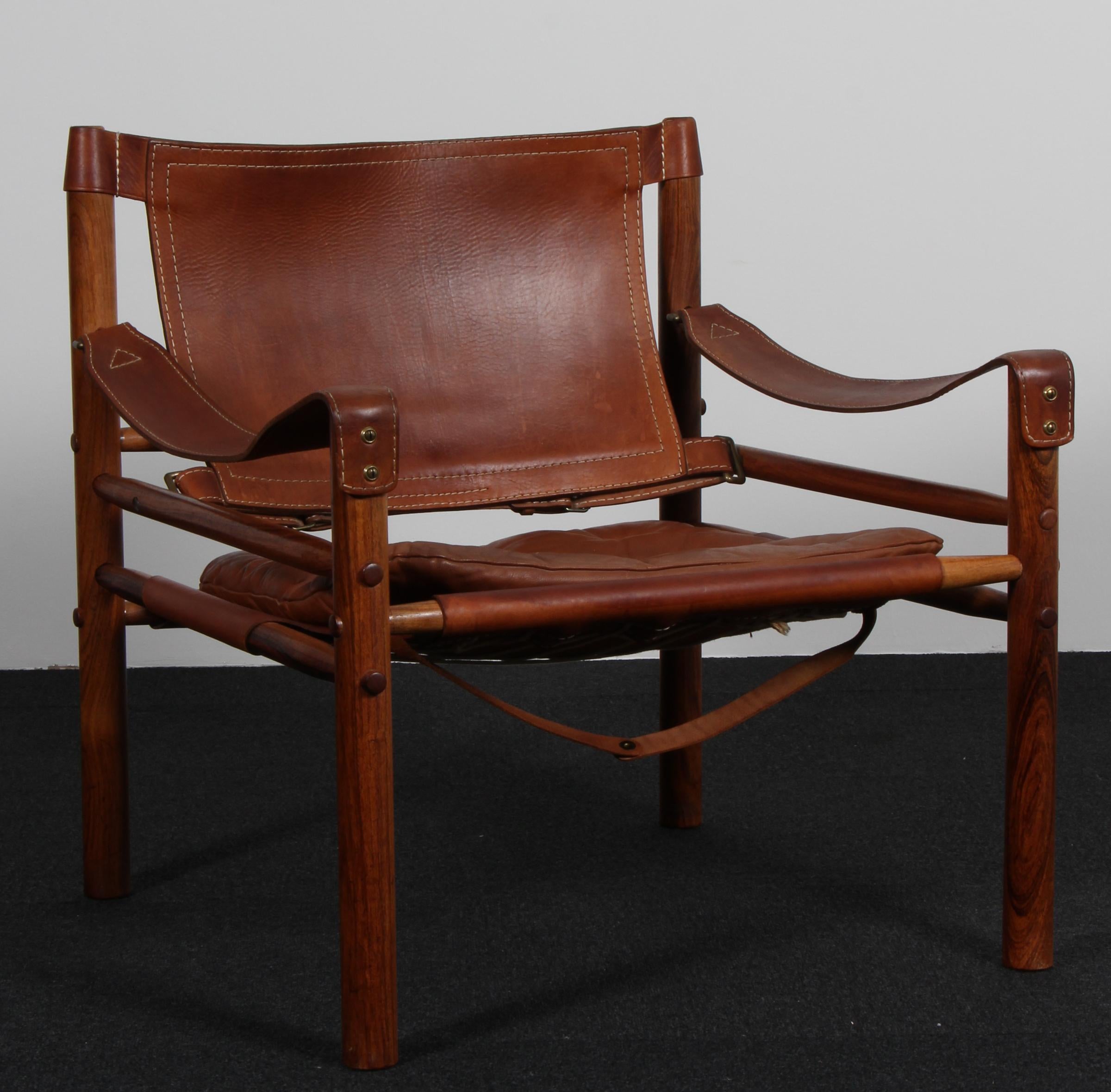 Arne Norell safari chair. Original upholstered foam cushions with patinated leather.

Frame of rosewood.

Model Scirocco, made by Norell.