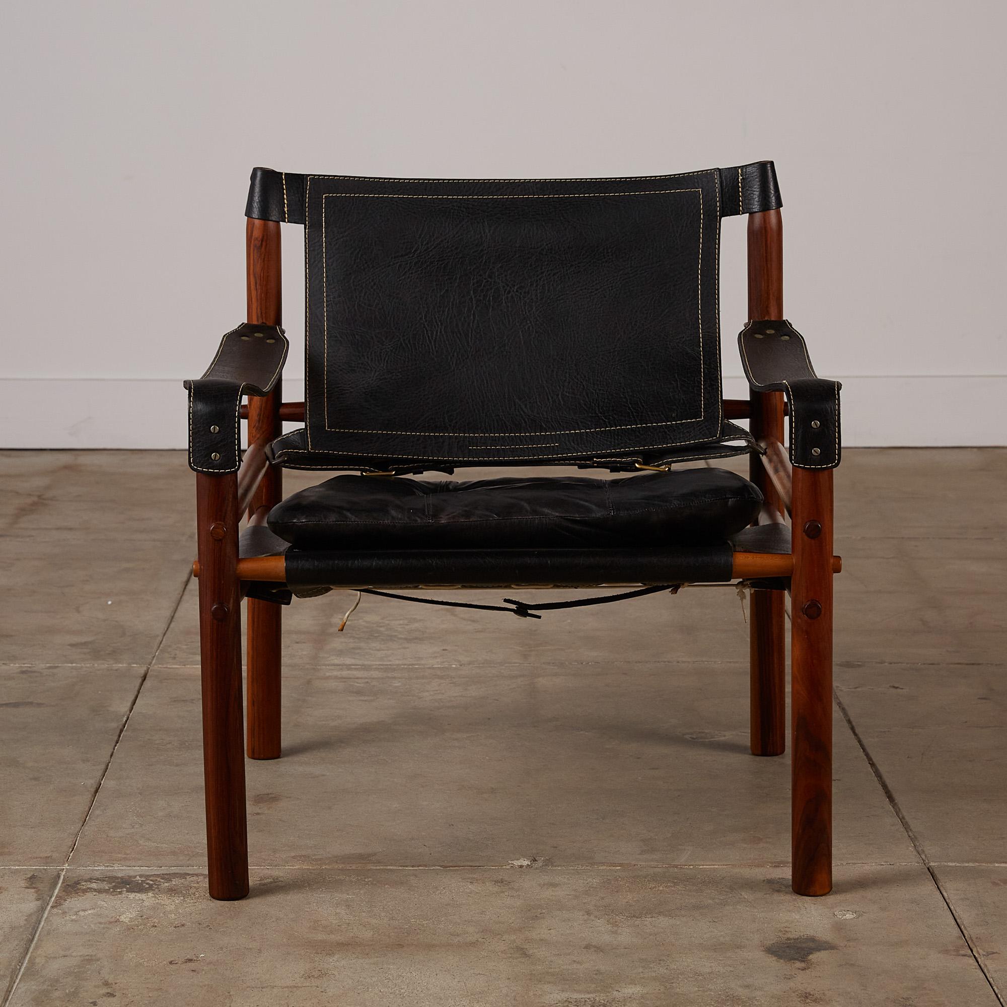 A 'Sirocco' safari chair designed by Arne Norell in 1966 and produced by Scanform in Colombia, a company licensed to manufacture the Sirocco chair for export to the US. This example features a solid rosewood frame strapped together by black-colored