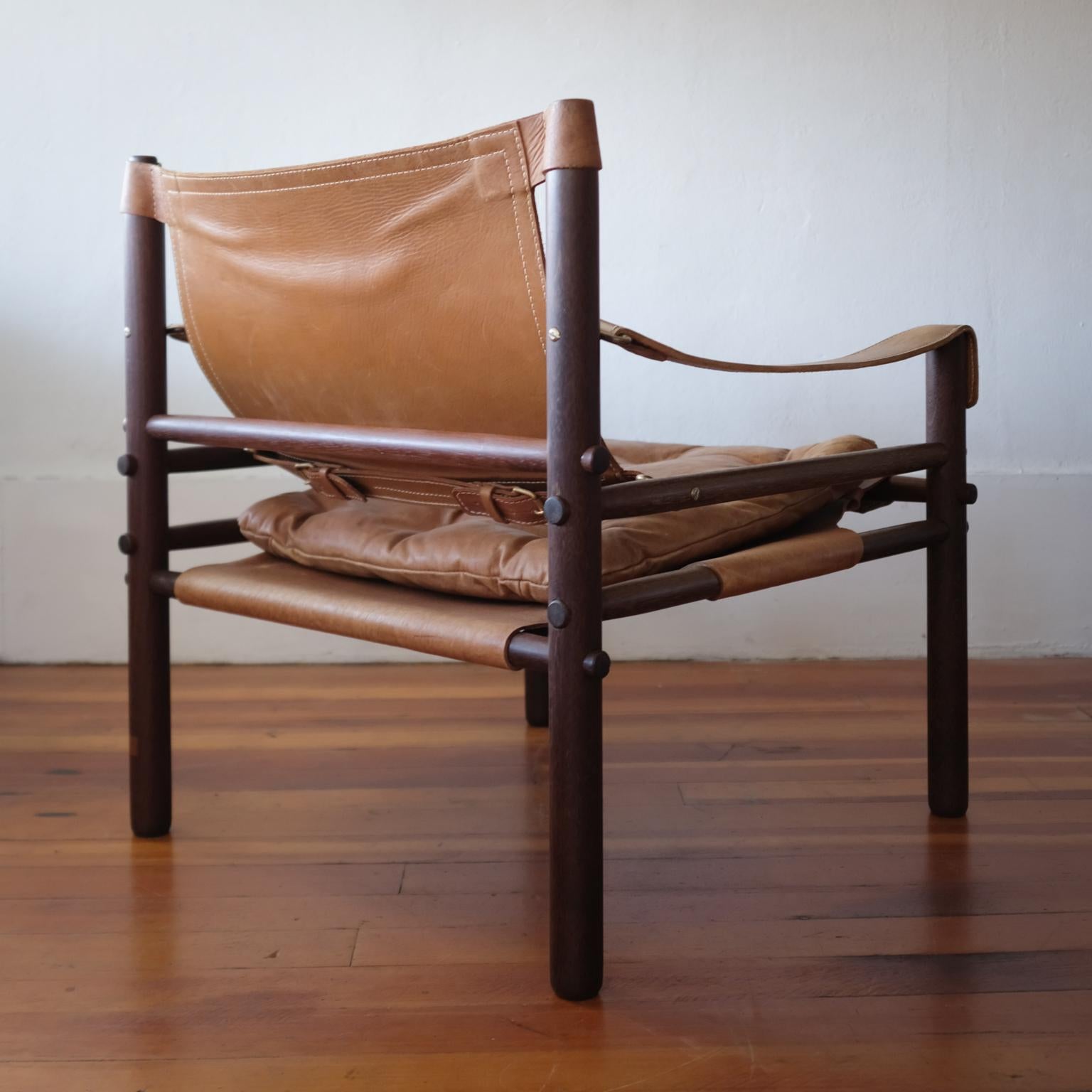 Sirocco Safari Chair by Swedish designer Arne Norell. Beautifully worn Cognac leather on an African Wenge frame. Tufted leather seat cushion and brass hardware. Unmarked, but presumably produced by Scanform in the late 1960s.