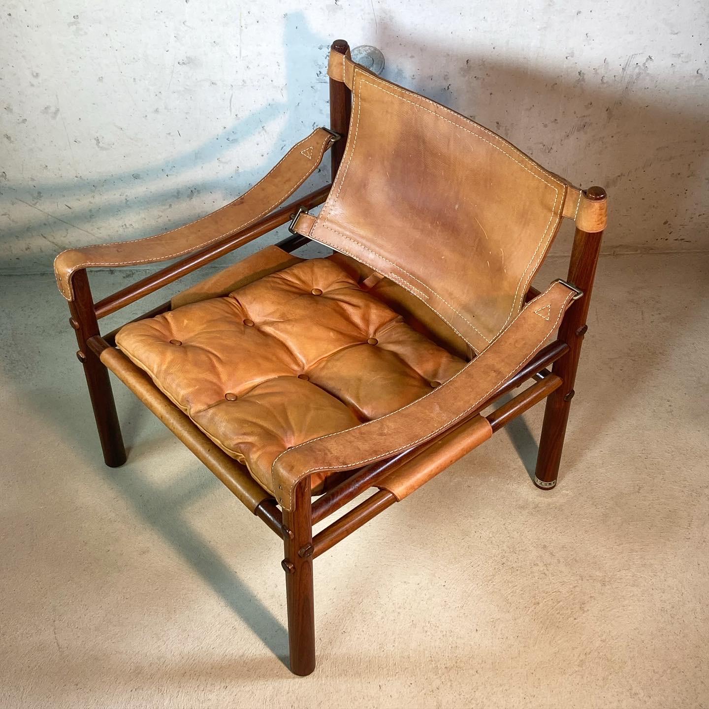 A 'Sirocco' safari chair designed by Arne Norell in 1966 and produced by Norell in Sweden in the 1970s. This beautifully patinated piece features a solid rosewood frame strapped together by leather slings with brass fittings and a removable tufted