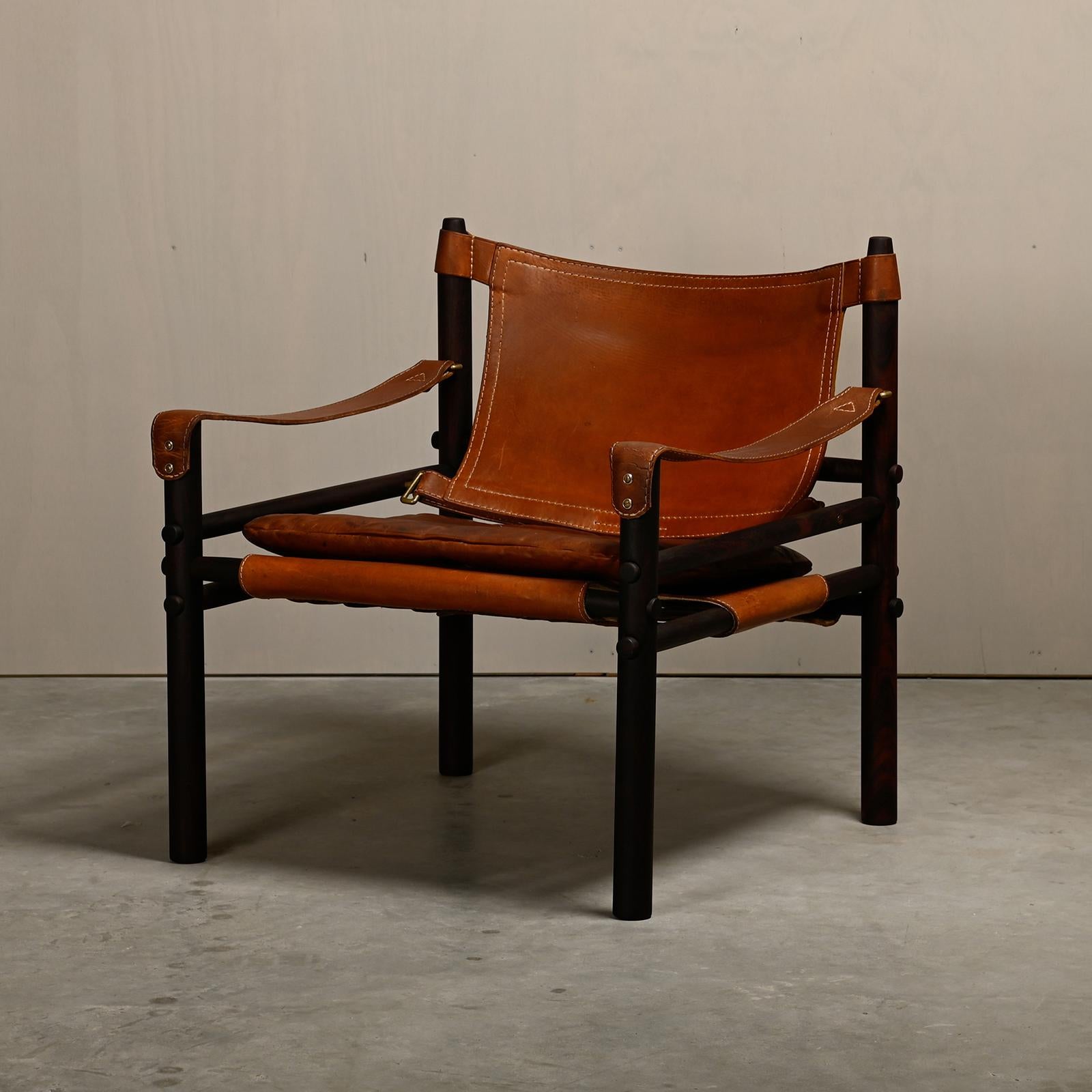 Sirocco Safari Lounge Chair, entworfen von Arne Norell und hergestellt von Norell Möbel AB in Schweden. Neu lackierter dunkelbrauner Palisanderrahmen mit den originalen Lederkissen in schönem, gealtertem braunem Leder. Alle in gutem Vintage-Zustand.