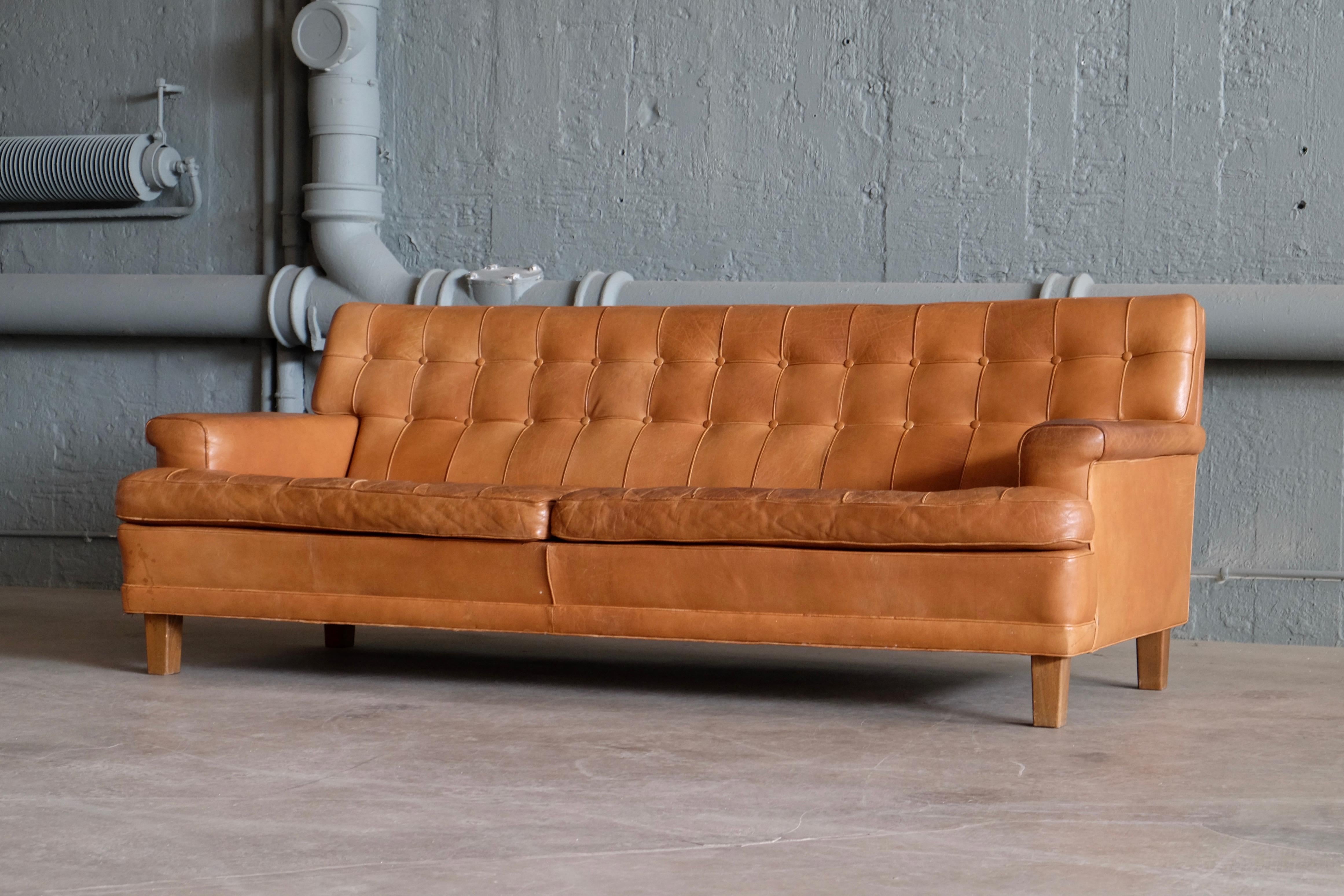 This fantastic sofa is designed by Arne Norell and produced by Arne Norell Möbler, Sweden.
Dark stained beech and cognac brown buffalo leather. Very good vintage condition with sign of usage and nice patina.
 