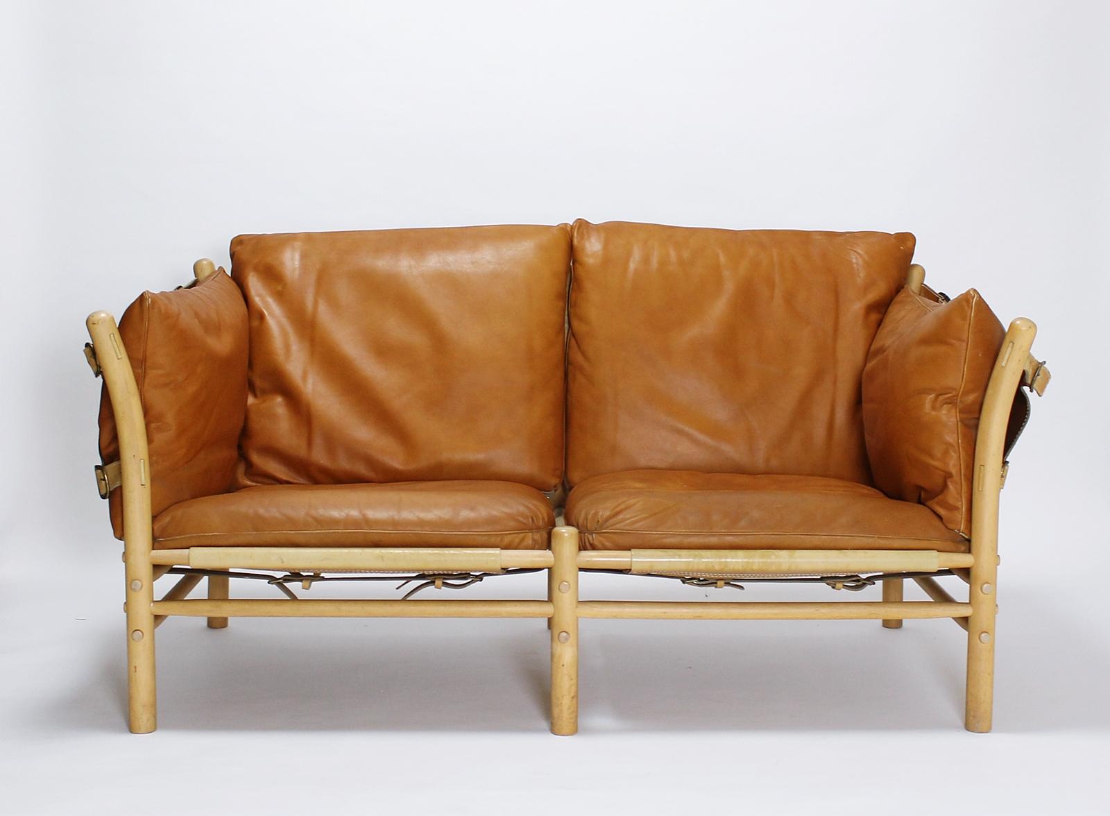 Arne Norell' s design Ilona two-seat sofa The frame is solid and turned ash, held together by a strong leather support, featuring fiber padded cushions with removable mid-brown leather upholstery.
In good original vintage condition with minor