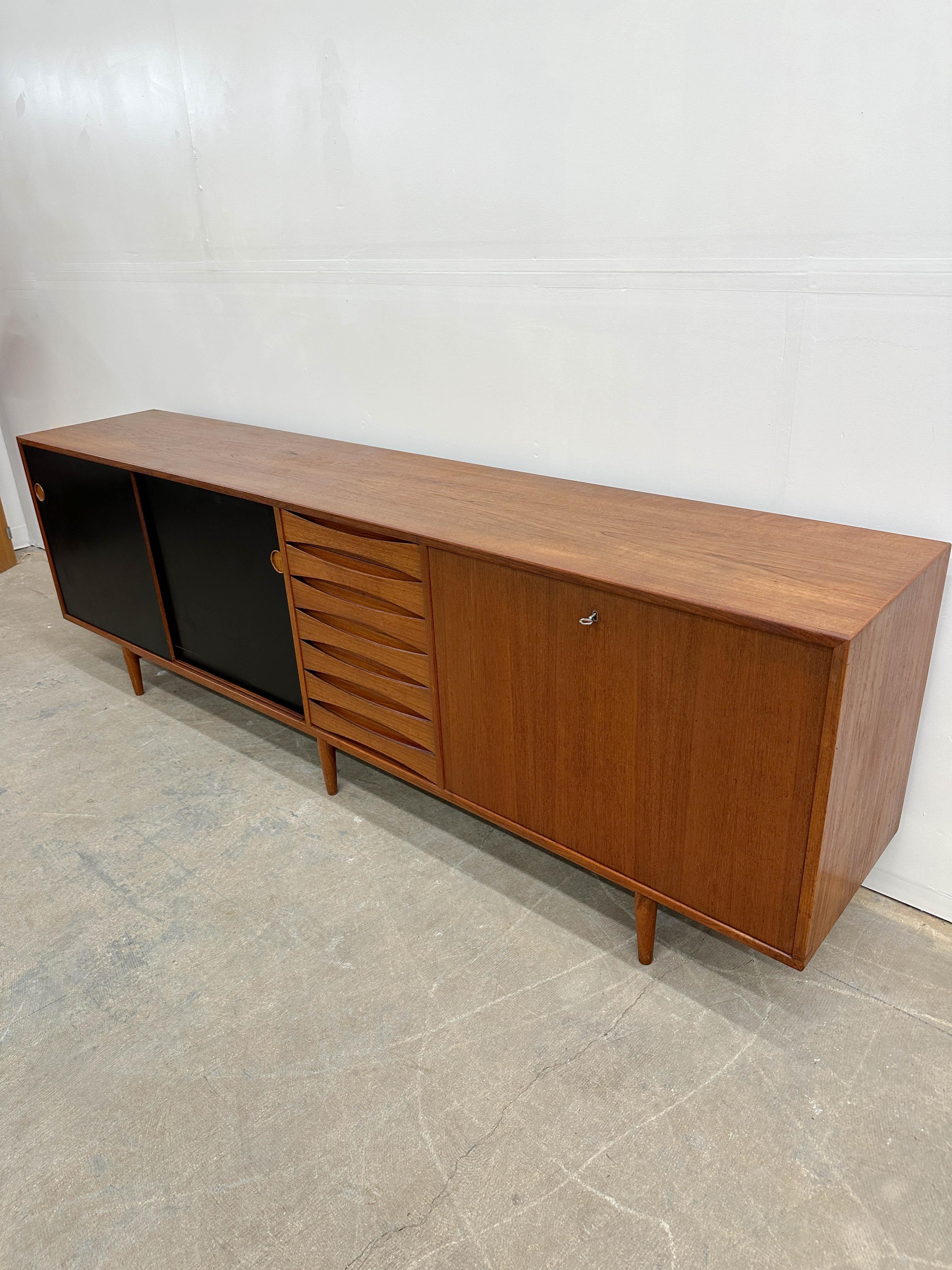 Grande crédence iconique d'Arne Vodder en teck pour Sibast vers 1955. Belle valise en teck avec portes réversibles teck / formica noir. Excellent rangement avec des étagères réglables derrière les deux portes coulissantes, sept tiroirs à la façade