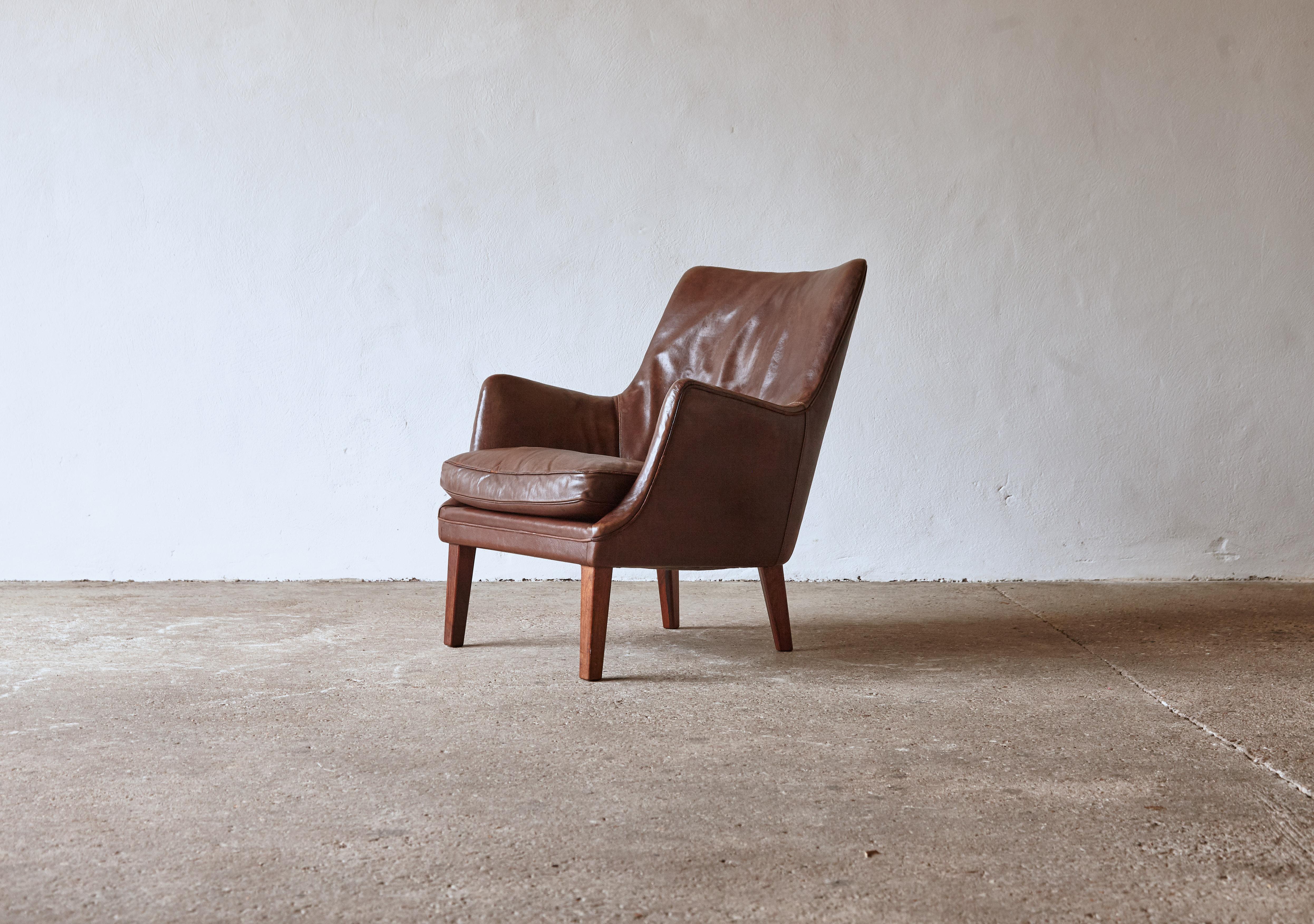 Arne Vodder armchair in original brown patinated leather with rosewood legs, produced by Ivan Schlechter, Denmark, 1950s. In good original condition with a nice tone and patina. Minor wear and losses to leather piping. Fast shipping worldwide.


