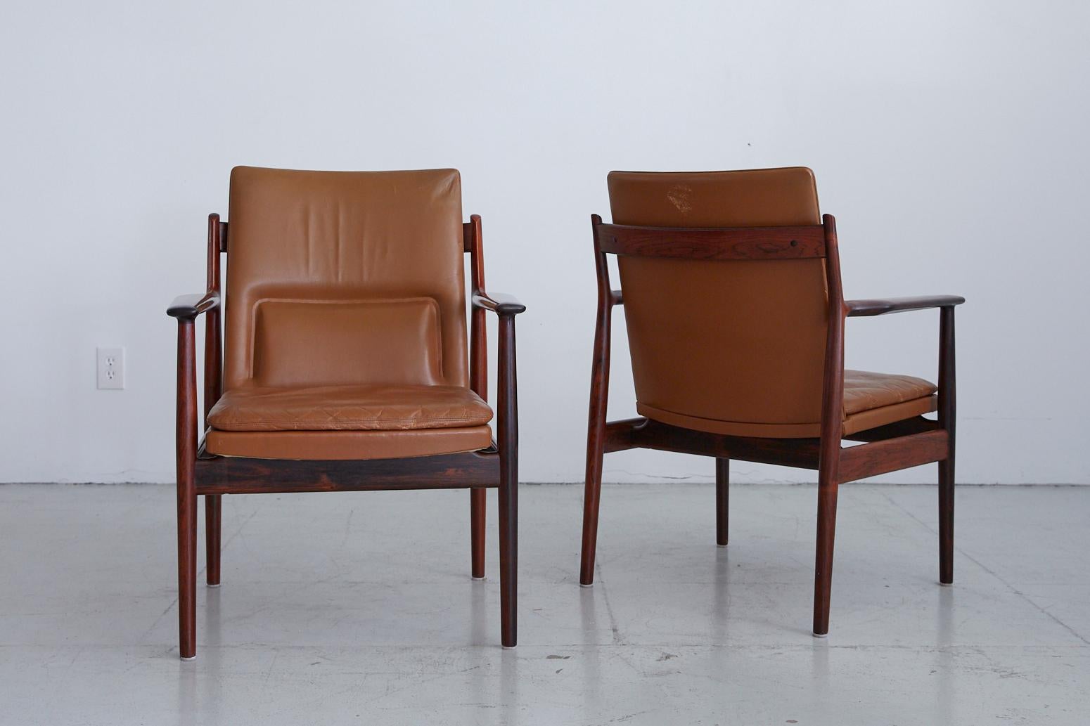 Handsome pair of armchairs designed by Arne Vodder. Beautiful rosewood frames with original tan leather seat with great coloring and patina.