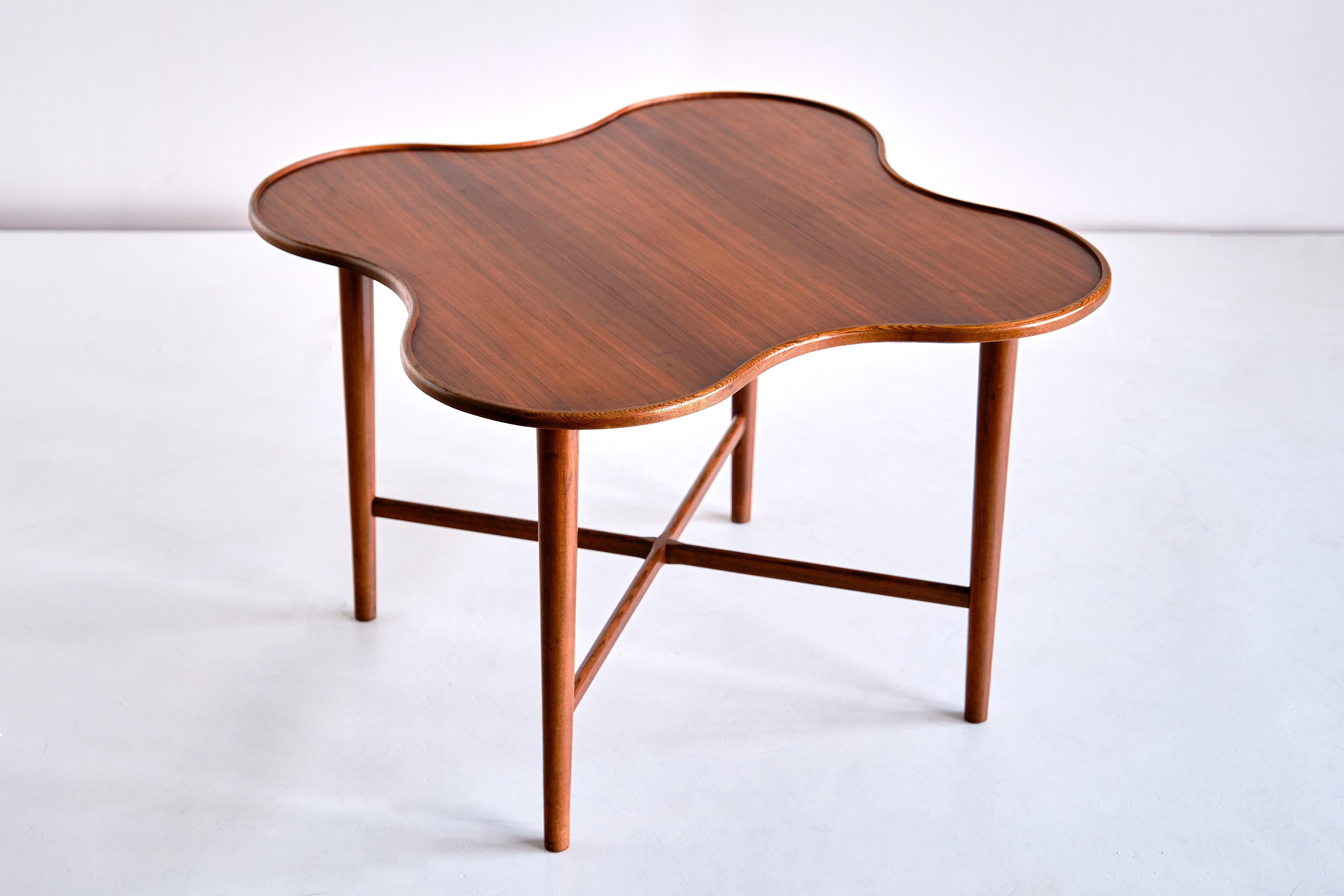 This very rare side table was produced in Denmark in the early 1960s. The design is attributed to Arne Vodder, produced by the manufacturer Bovirke. The quatrefoil shape of the top, executed in a beautifully veneered teak wood, gives the table a