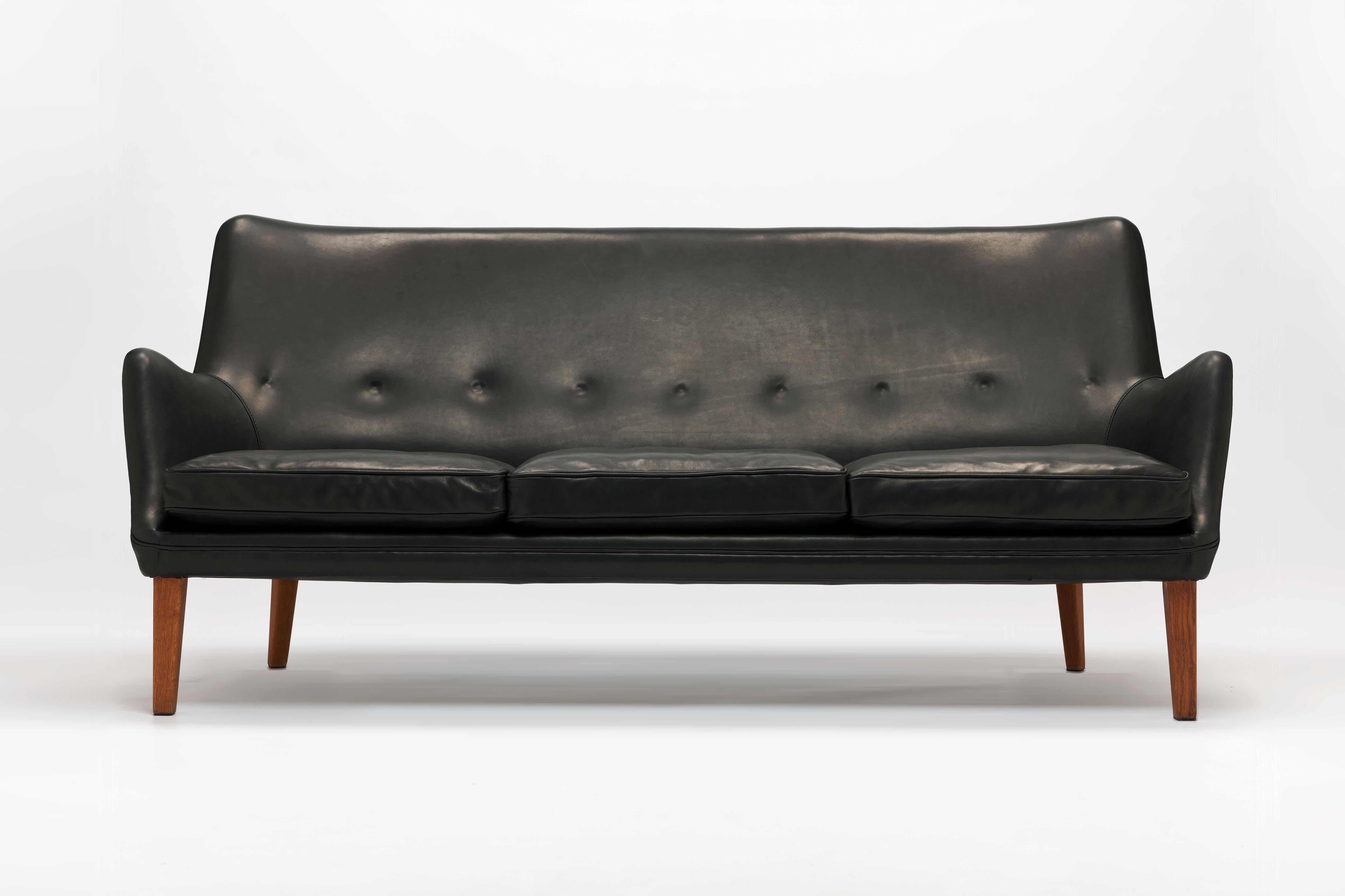 Black leather 3-seat sofa model AV53 / 3 by Arne Vodder, designed in 1953 for Ivan Schlechter, Denmark. 

The sofa has a slightly curved backrest that flows smoothly into the upwardly positioned armrests. The seat consists of 3 loose down-filled