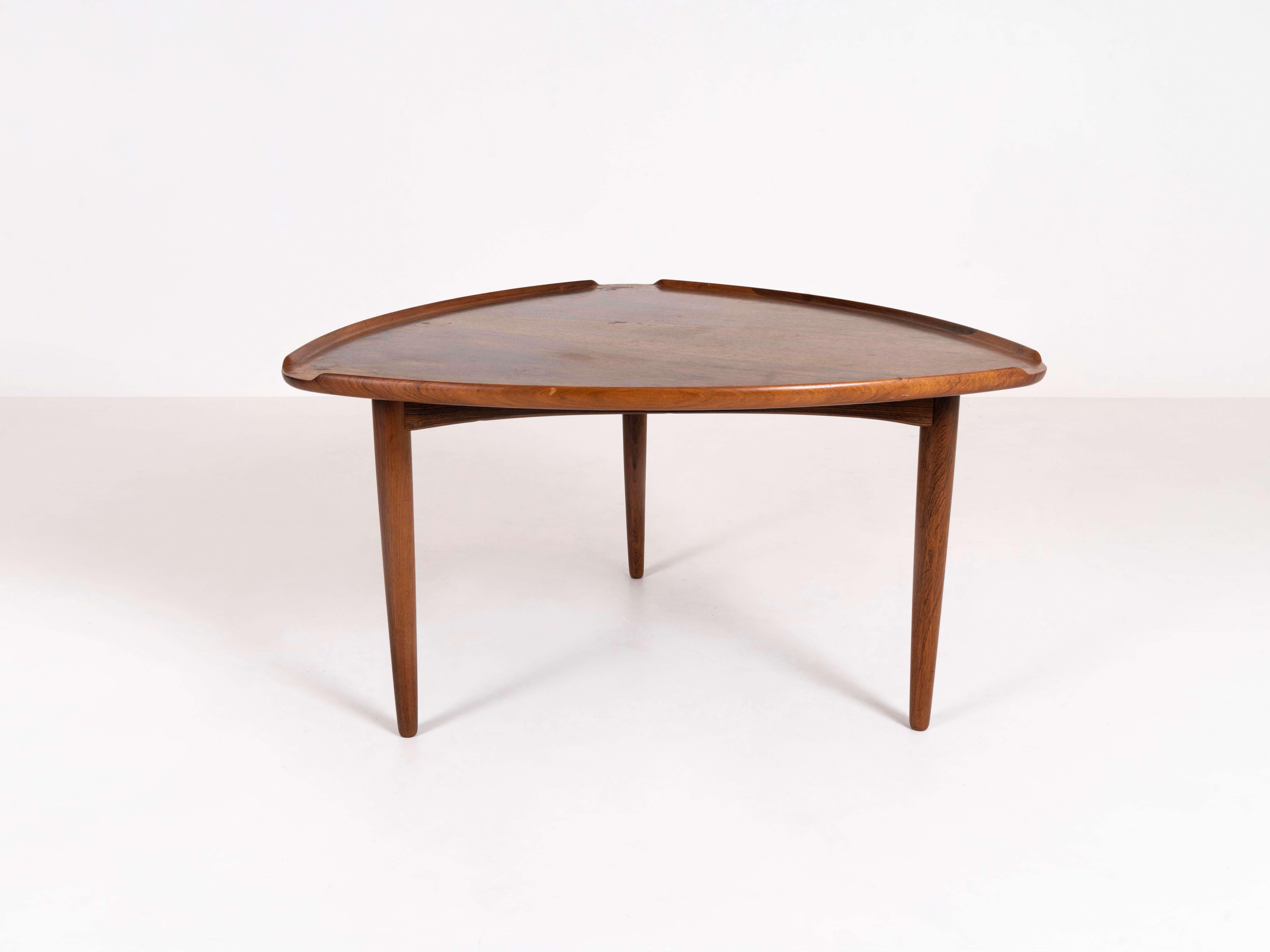 Triangular coffee table in rosewood designed by Arne Vodder for Silkeborg. This vintage coffee table from Denmark in the 1950s, has an interesting shape with profiled edges on the sides. It has three cone-shaped legs. It is in good condition with