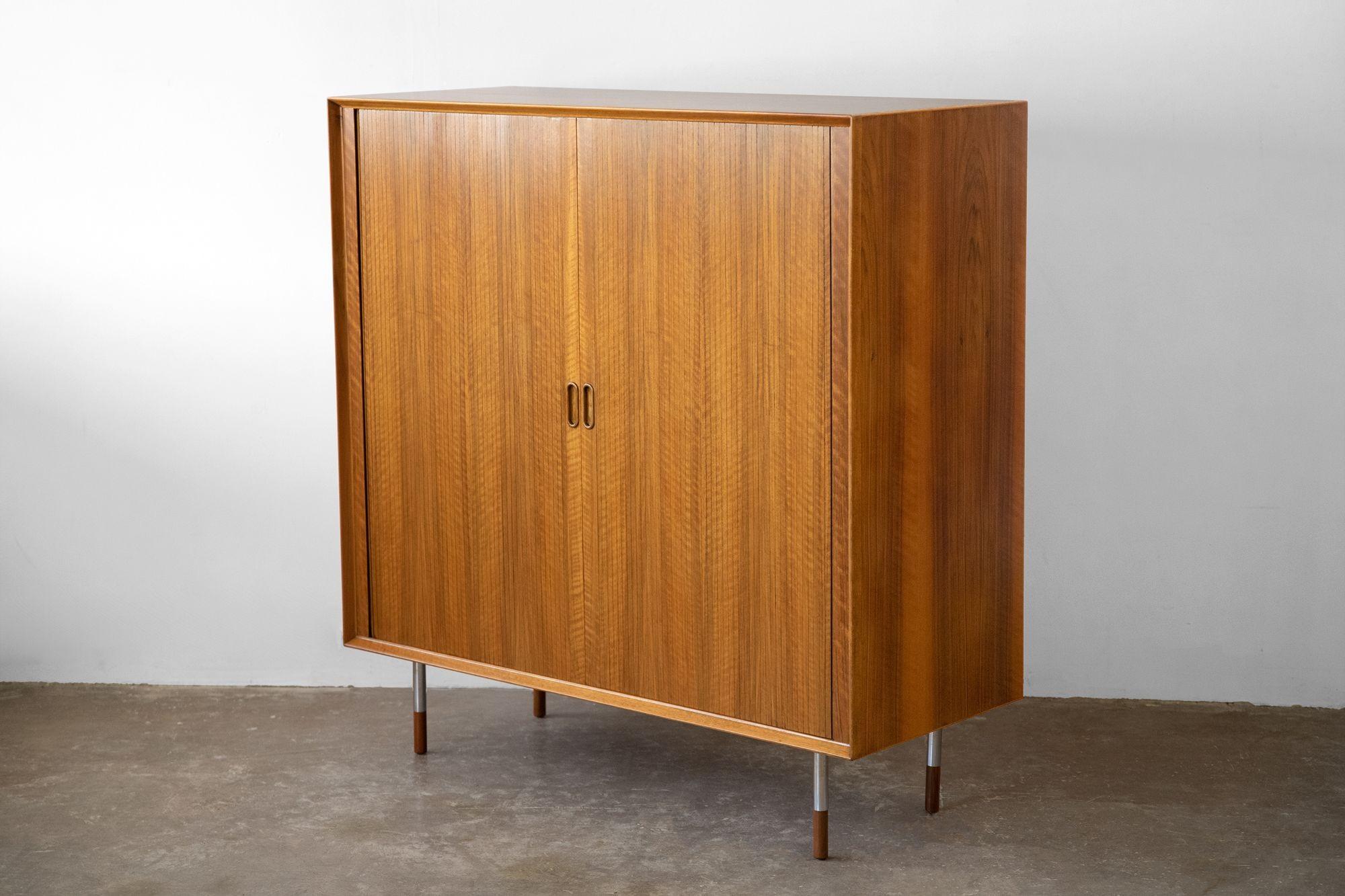 Exquisitely crafted upright storage cabinet designed by Arne Vodder and produced by Sibast of Denmark. 
The tambour doors are very well constructed and function smoothly and as intended. This is an early example with the more desirable petite steel