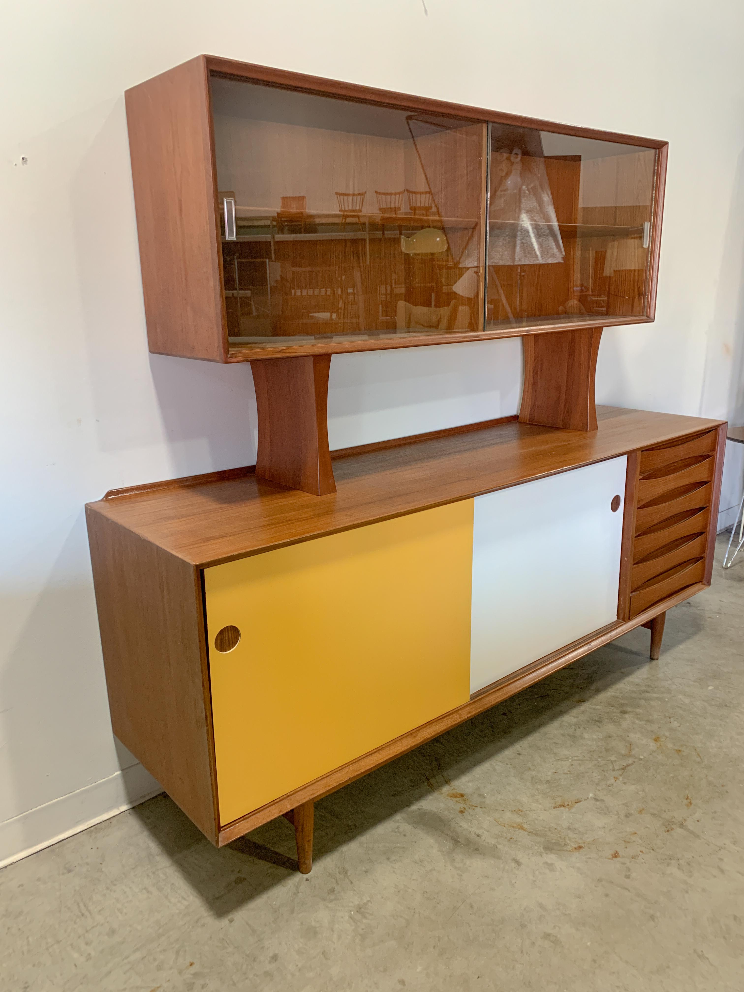 Striking teak and color panel Model 29 sideboard/credenza with hutch, both designed by Arne Vodder for Sibast. Sculpted drawer fronts, adjustable shelves and sliding doors make this a very versatile piece. The glass doors on the top piece can also