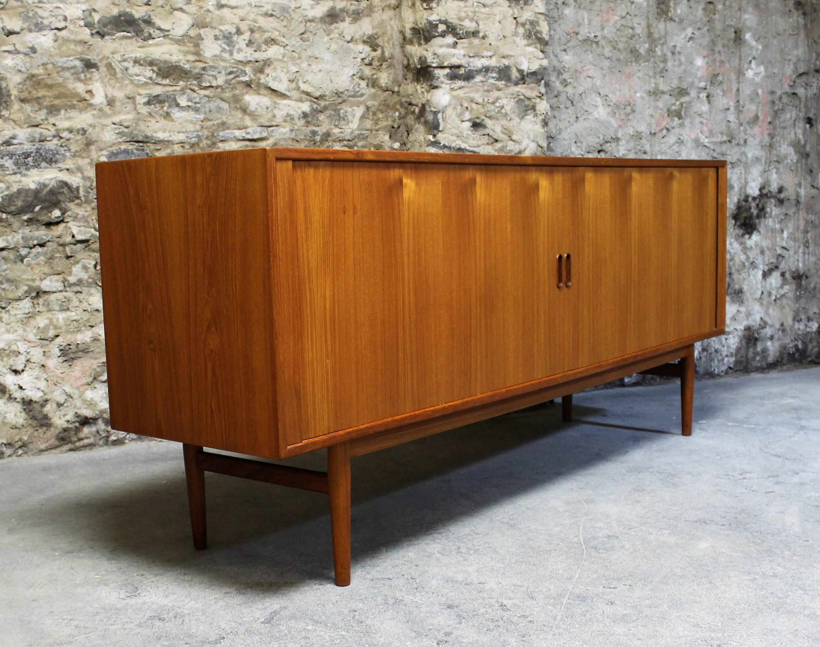 Mid-Century Modern credenza designed by Arne Vodder for Sibast. Labelled with the maker's mark and Danish control emblem. Featuring beautifully aged teak wood and tambour doors that glide back into the cabinet giving unobstructed access to the