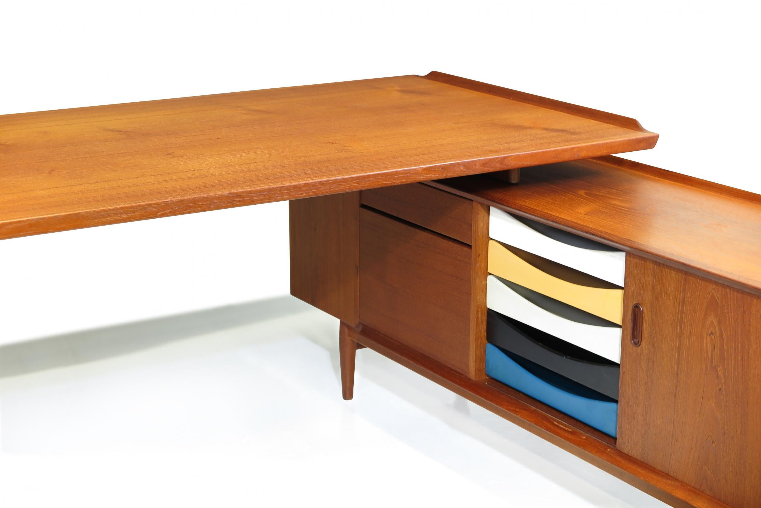 Mid Century Scandinavian executive desk and credenza designed by Arne Vodder for Sibast Mobelfrabrik, Denmark. Crafted of teak with raised edge and integrated sideboard. The desk has a locking drawer and filing cabinet; credenza return with cabinet