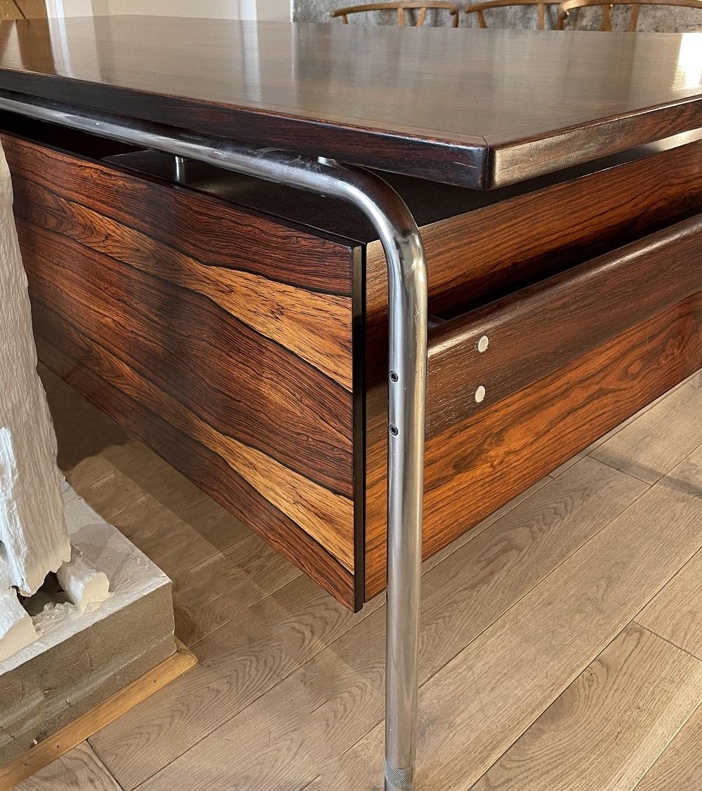 Rosewood desk by Arne Vodder for Sibast. This rosewood desk has a very nice look thanks to the wood grain and the use of chromed metal brings a modern touch to the desk which makes this piece of furniture a very Scandinavian design. In addition,
