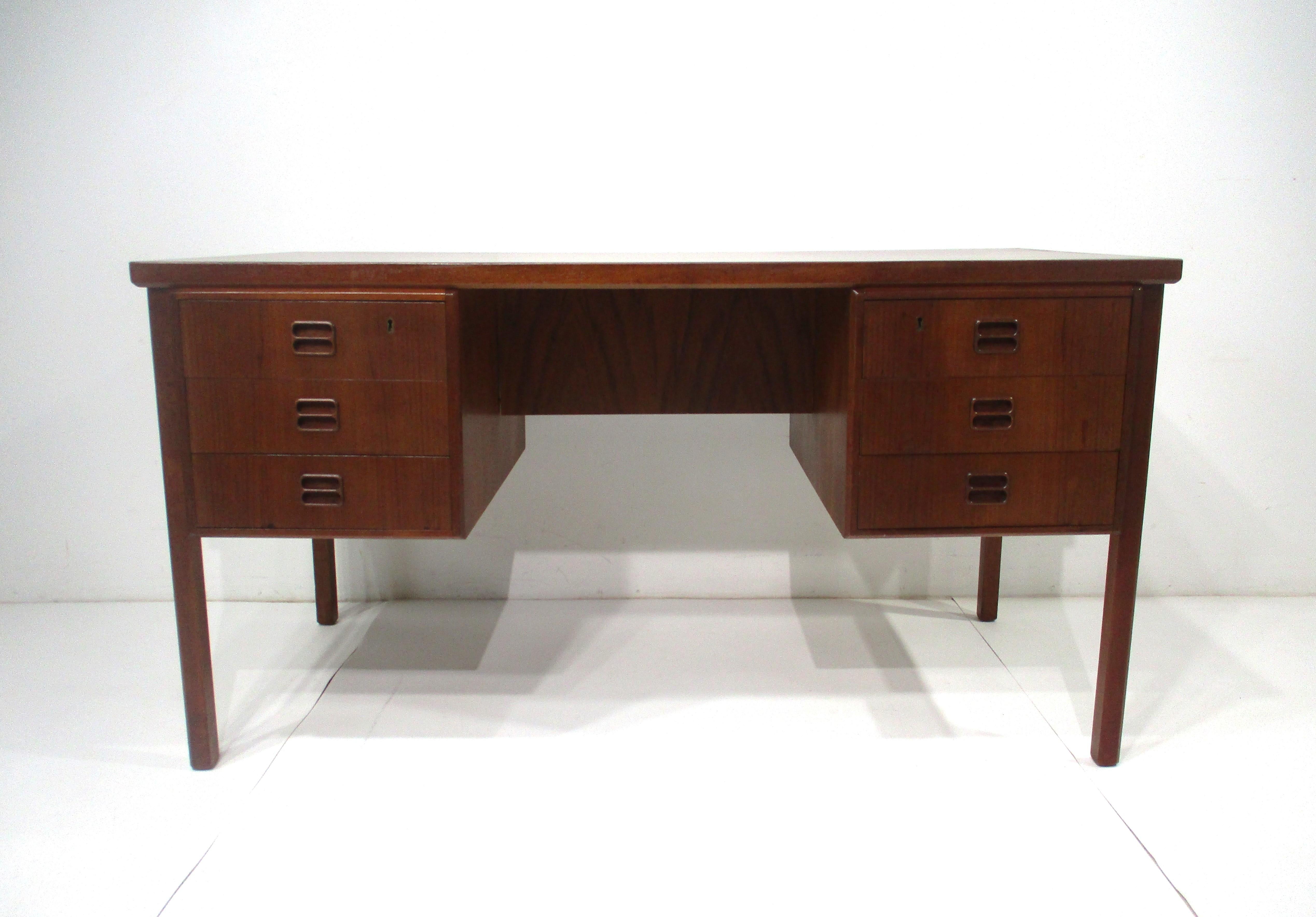 A dark teakwood executive desk with three drawers to each side and inset finger pulls to the fronts, the back side has two small bookcase cubies . The perfect desk for home or office because of it's European scale which is smaller that the American