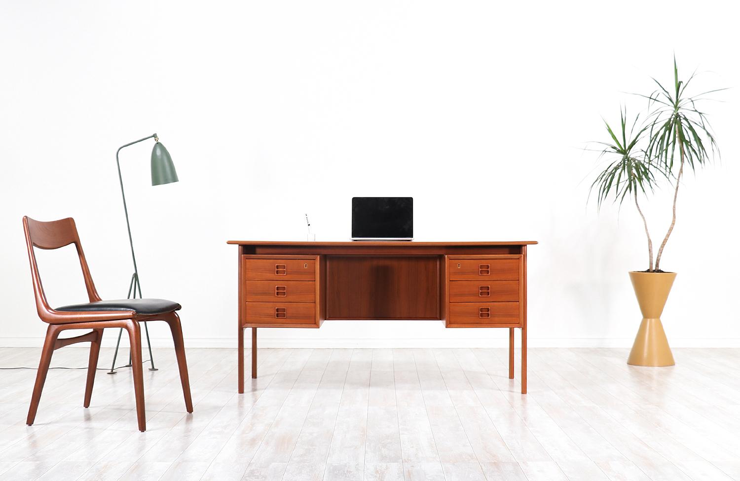 Elegant modern executive desk designed by Arne Vodder for Sibast in Denmark, circa 1950s. This striking design features a teak wood frame with three spacious drawers on each side and an open bookshelf in the back for additional storage and display