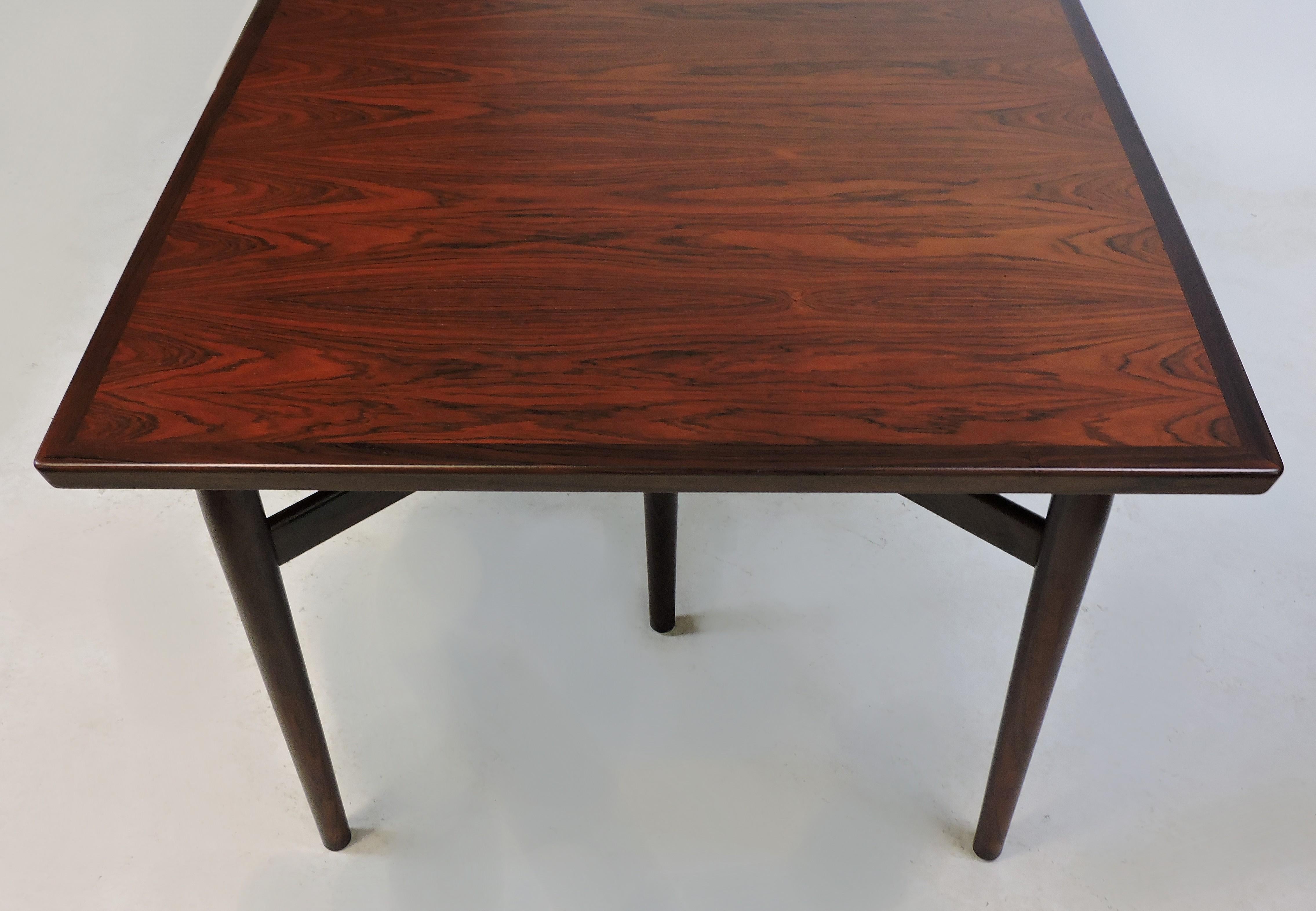 Elegant expandable dining or conference table in rosewood designed by Arne Vodder and manufactured in Denmark by Sibast. This table has a beautiful active wood grain and two self-storing leaves. It expands from 78 3/4 inches to 98 1/4 inches with