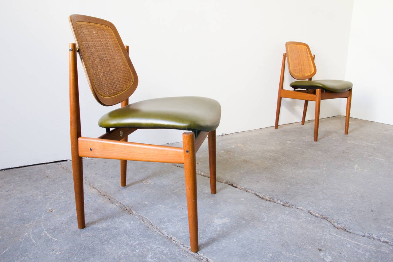 A set of four model F-205 chairs in teak by Arne Vodder for France & Son. The backrests are cane, framed by teak, and swivel via brass hinges. The curved seats are form-fitting, and achieve a stunning floating effect with the help of concealed dowel