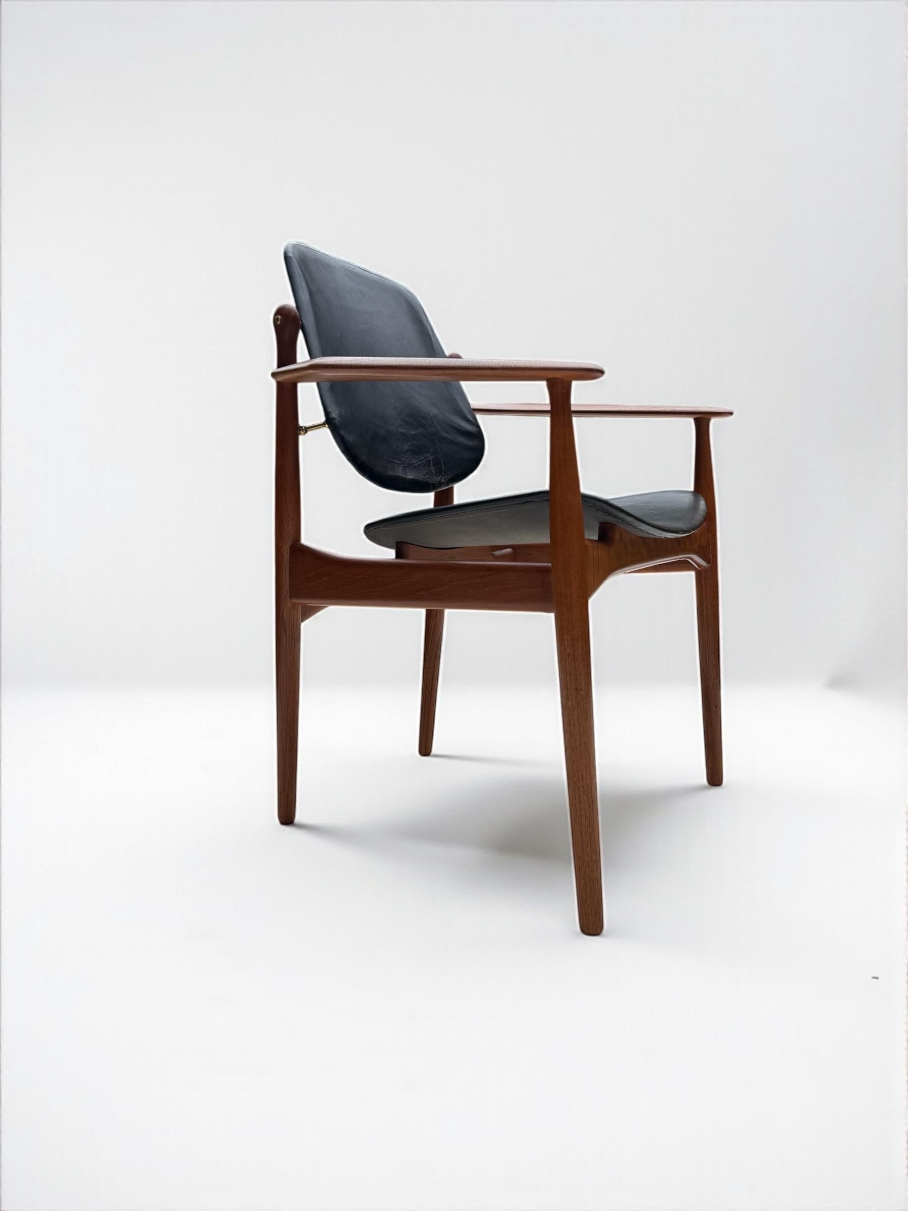 This armchair designed by Arne Vodder employs ample innovative concept and a sculptural silhouette. made with a Teak frame and sculptural armrests, upholstered in smooth leather in vintage condition possibly the original upholstery with some minor