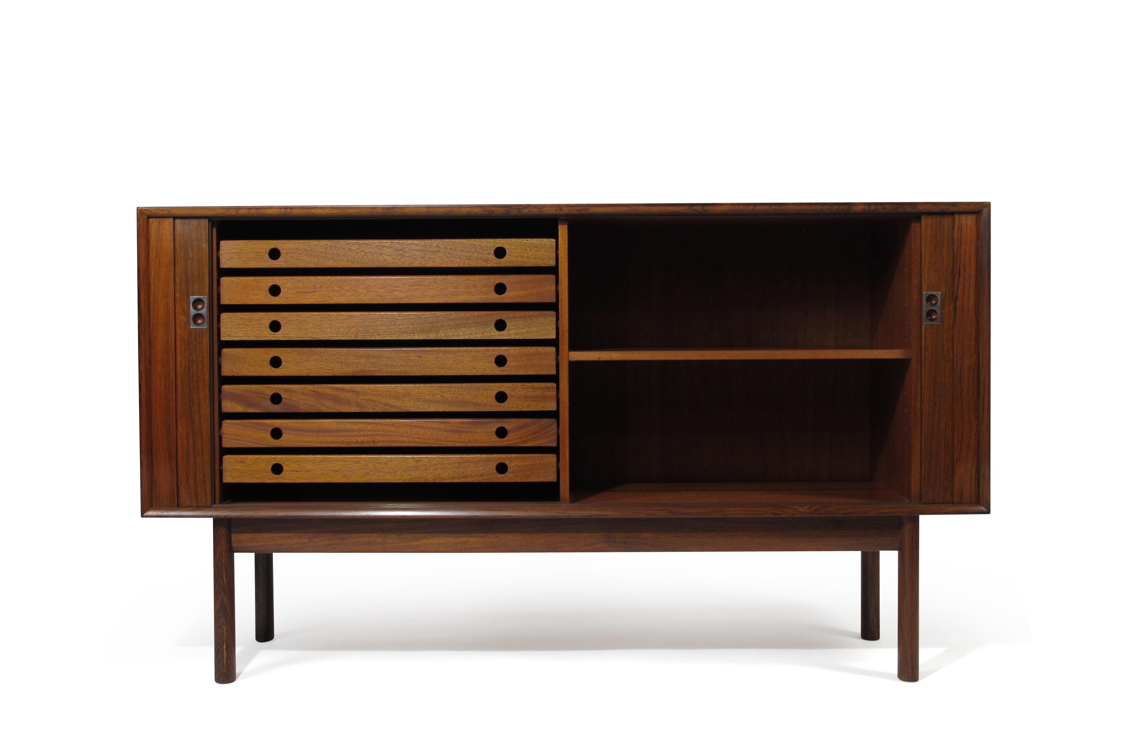 Arne Vodder for Sibast rosewood credenza with mitered corners, sliding tambour doors and metal pulls. The interior features a mahogany interior with adjustable shelf and seven silverware drawers. The cabinet has been lightly restored and in good