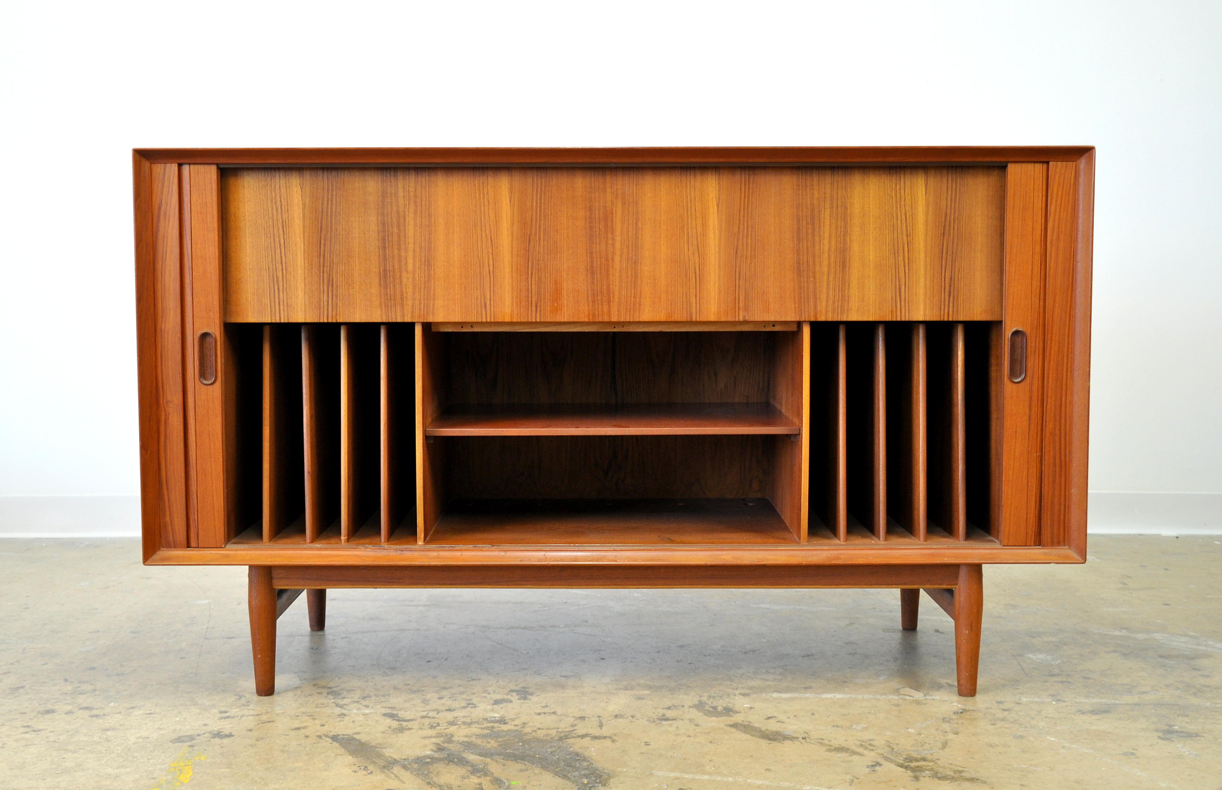 A rare Danish modern teak entertainment console or hifi stereo music cabinet designed by Arne Vodder and manufactured by Sibast in the 1960s. The credenza, which can also be used as a dry bar, features tambour sliding doors opening to an interior