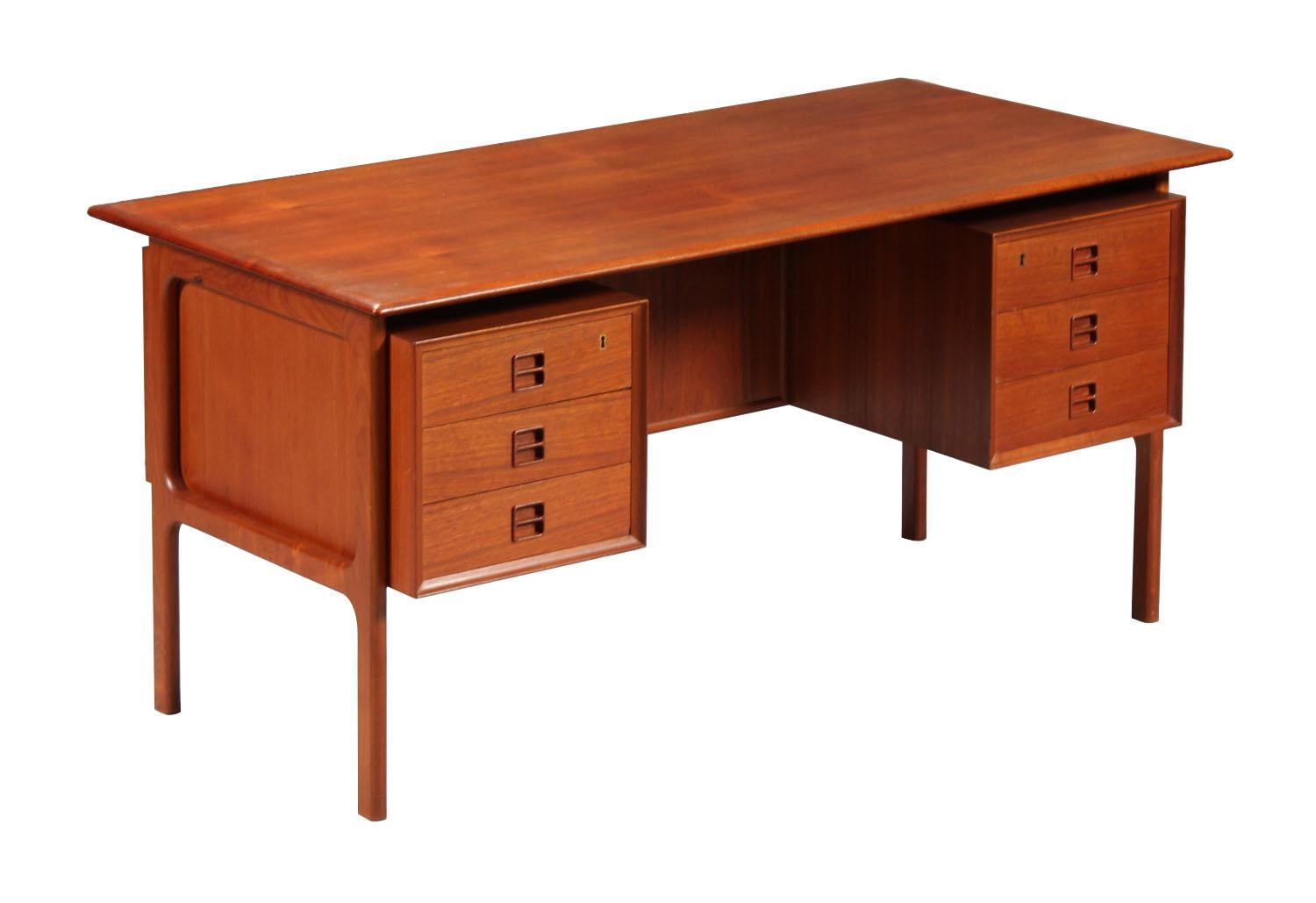 Freestanding writing desk designed by Arne Vodder

Nice rich colour teak veneer with solid teak legs' construction and profiles running along the edges. 

Front of the desk features six drawers two of which are lockable (key is included). Rear