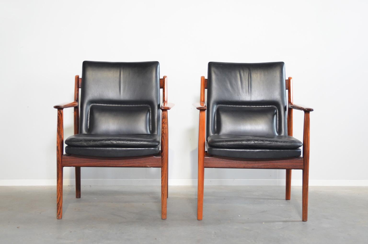Comfortable rosewood armchairs by Danish designer Arne Vodder. Rosewood frame with a black leather upholstery. The backrest has a built-in extra support for the lower back. The upholstery is original and in very good condition. The chairs are marked