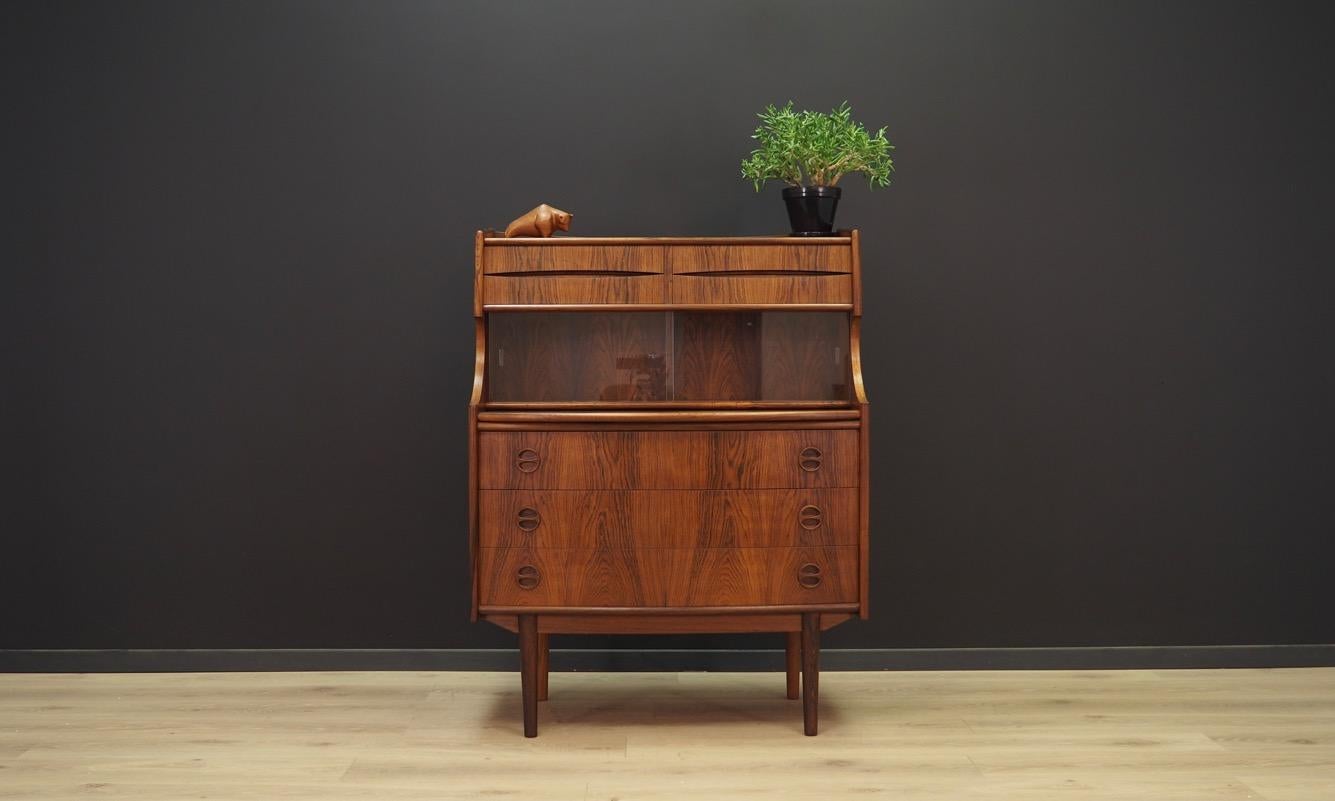 The unique 1960s-1970s secretary, designed by the leading Danish designer Arne Vodder. The surface of the furniture is covered with rosewood veneer. The secretary has three large drawers and four smaller, glass sliding doors and a pull-out top.