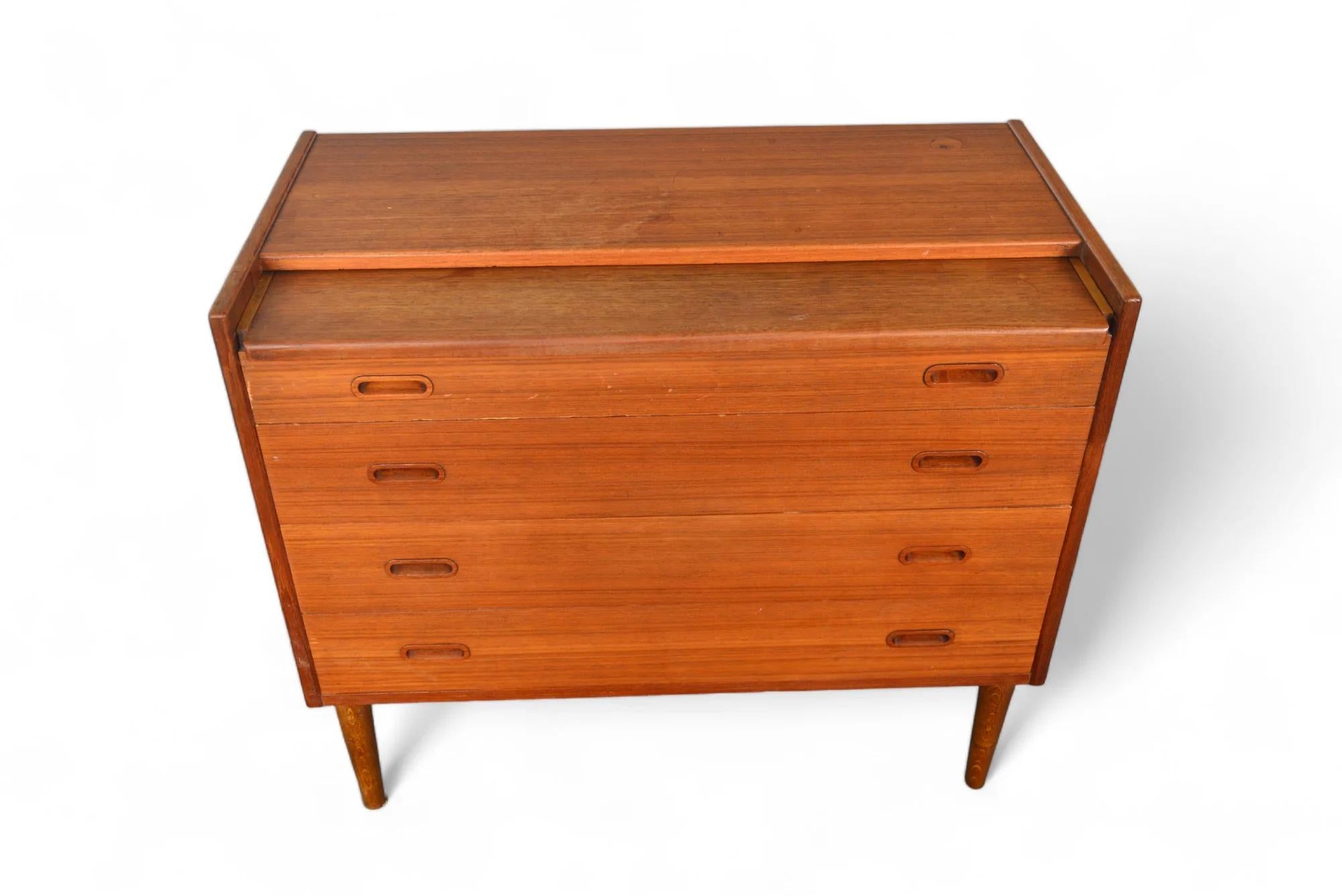 Designed by Arne Vodder in the 1960s, this Danish modern teak secretary is bursting with functionality! Top drawer pulls out to create a desk and when the top plate is lifted, a vanity mirror and divided makeup compartments are revealed. Three lower